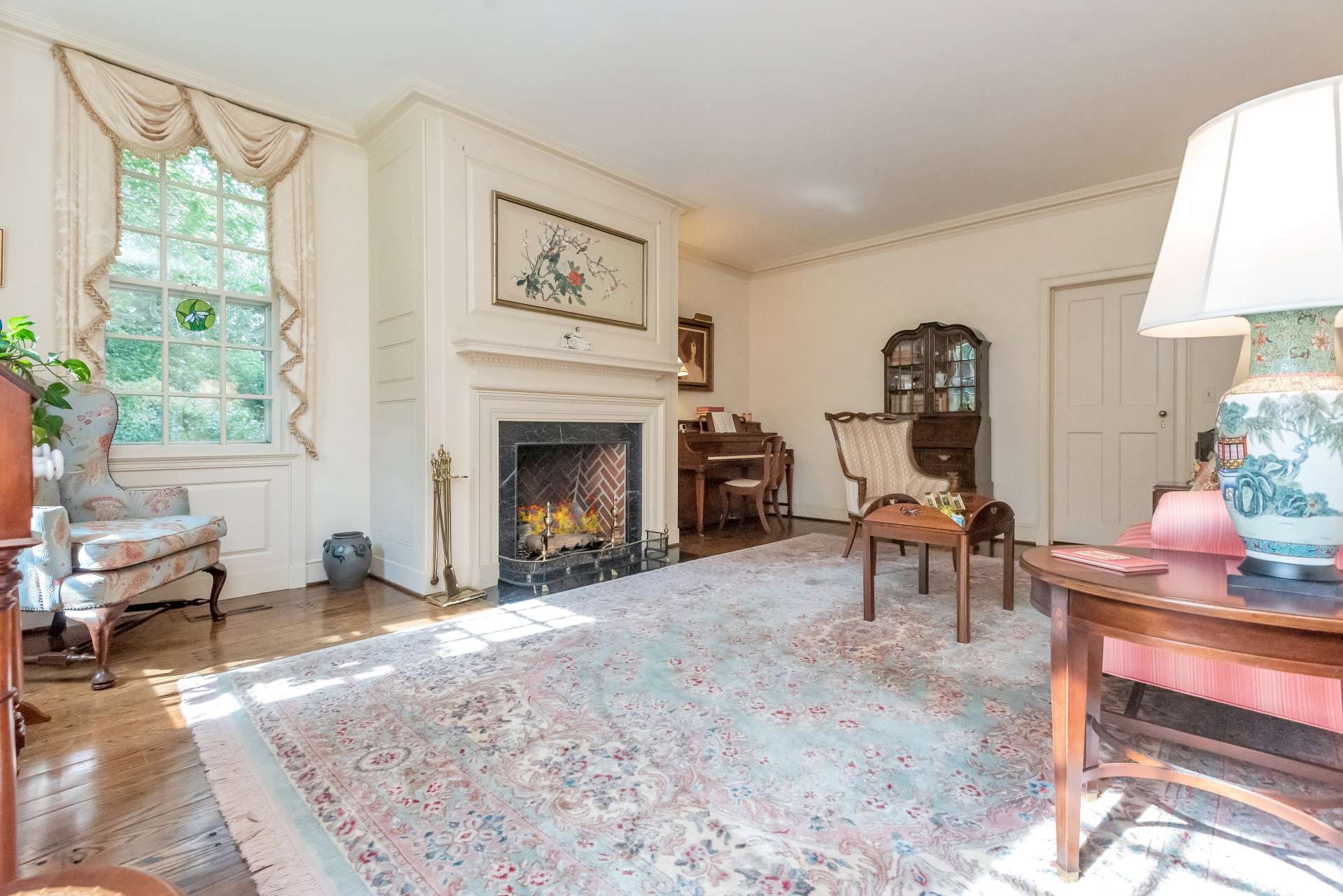 Step inside and be mesmerized by the large windows filling each room with natural light. This is the parlor with first of 3 fireplaces, each transitioned to gas logs.