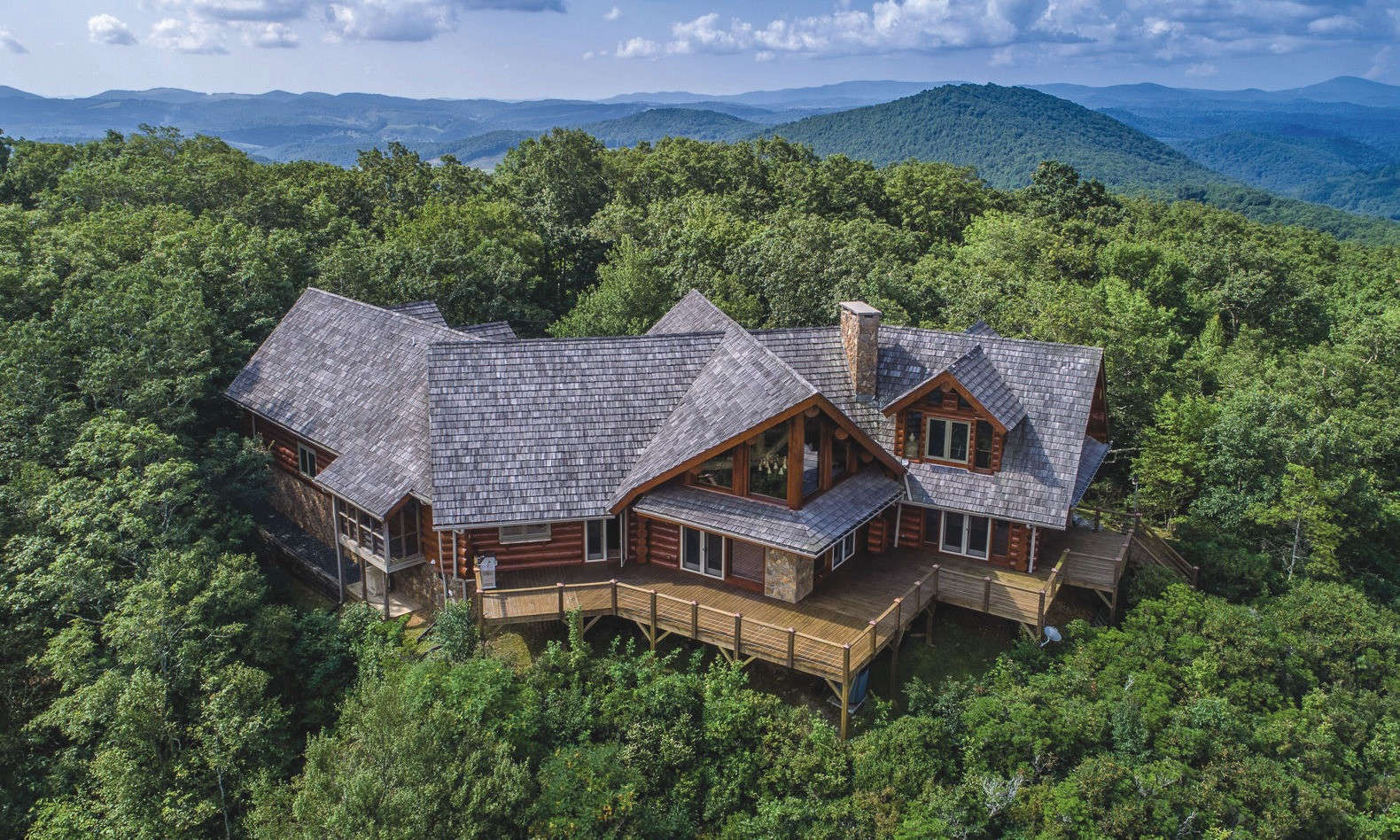 ENJOY PRIVATE AND ELEVATED LIVING with this rare opportunity to own the top of a mountain with one of the area's most architecturally significant log cabins and breathtaking panoramic long-range views!