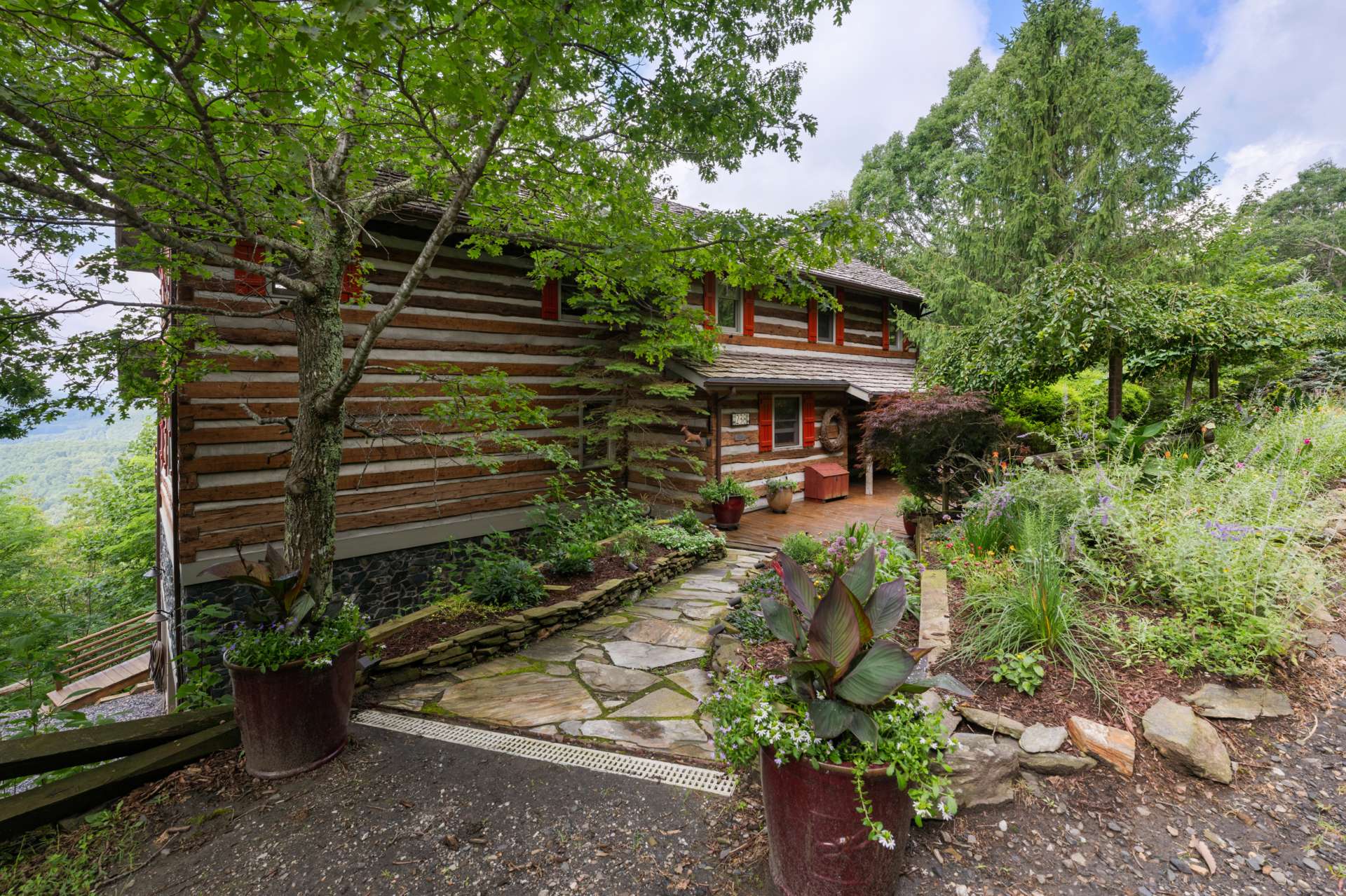 A flagstone path with landscape lighting leads to the charming entry patio, surrounded by layers of curated plantings and native trees for year-round beauty and privacy.