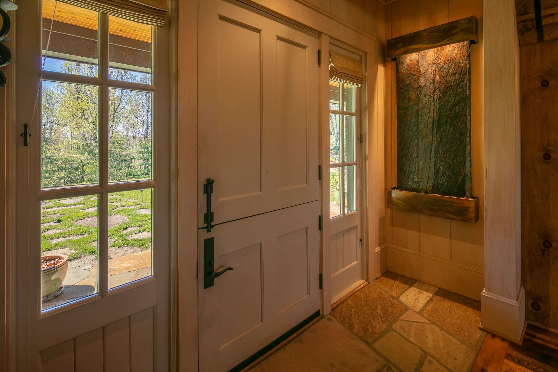 The main entrance features a Dutch door and a water fountain on the wall leading to a spacious great room which is flanked by two stacked-stone wood burning fireplaces with gas starters.