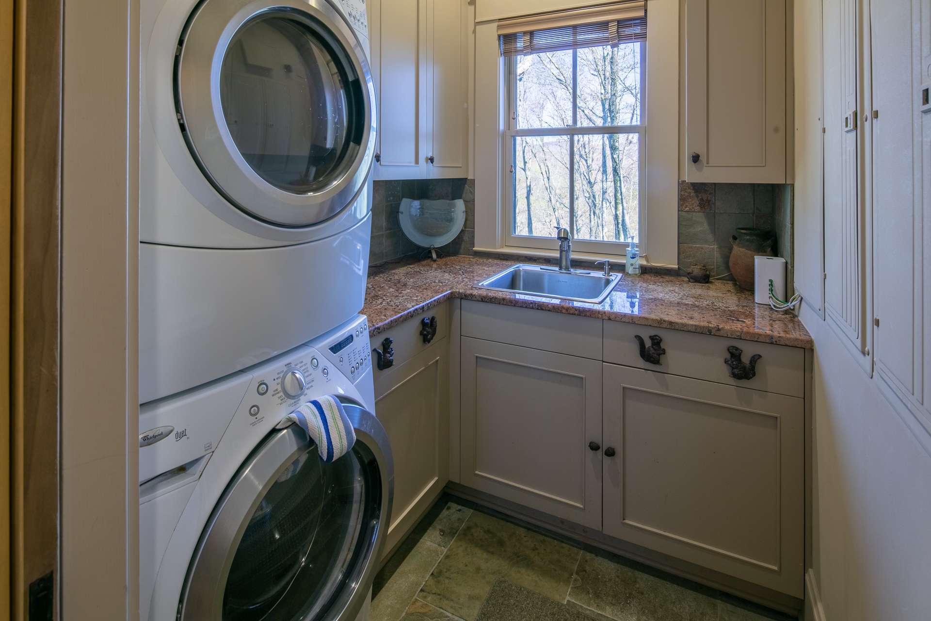 The Laundry room is conveniently located between the side entrance and kitchen.  It offers upper and lower cabinetry, granite counter top, sink and stacked Whirlpool washer and dryer.