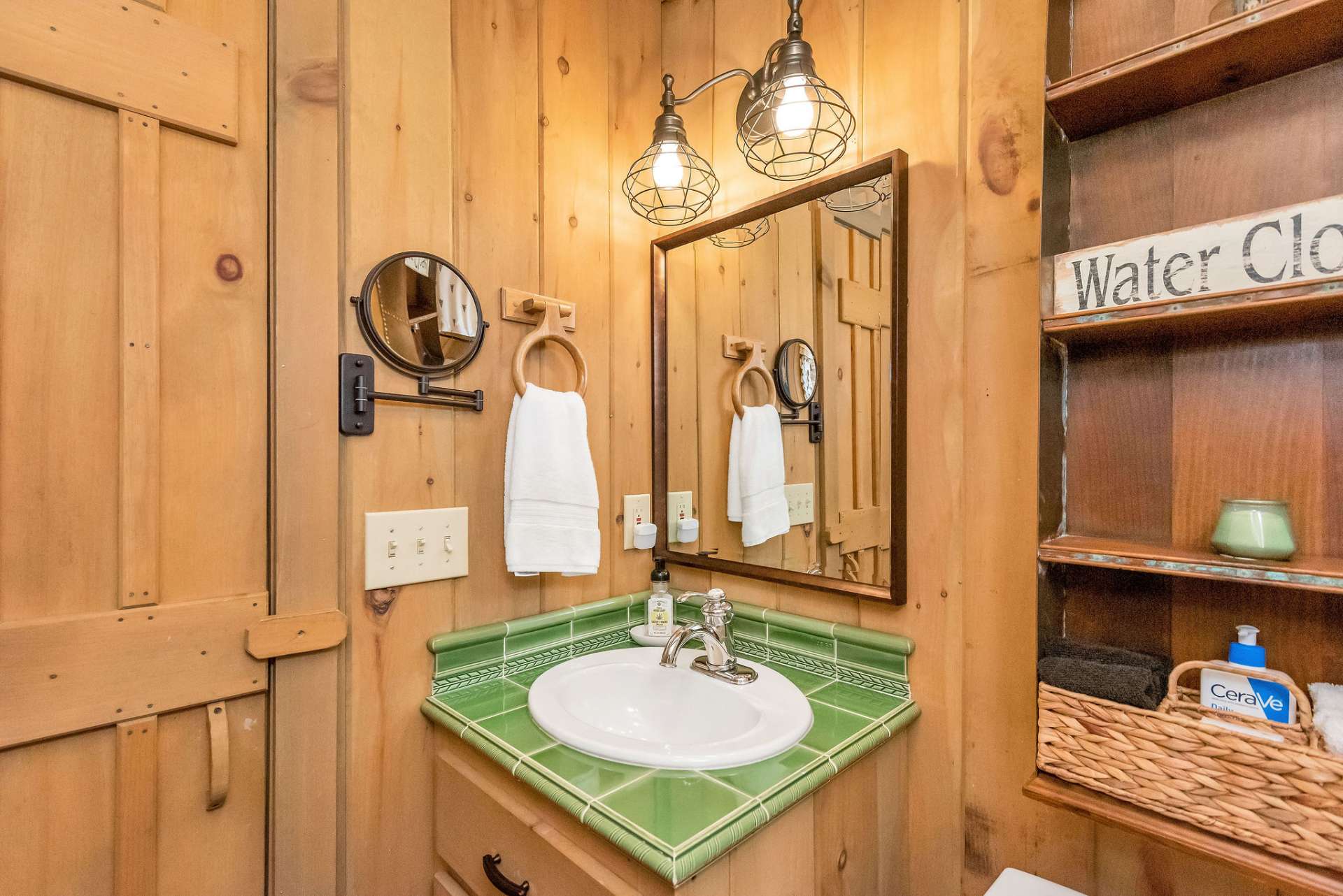 Unique green tile sinks and modern lighting carry continuity throughout the home's baths.