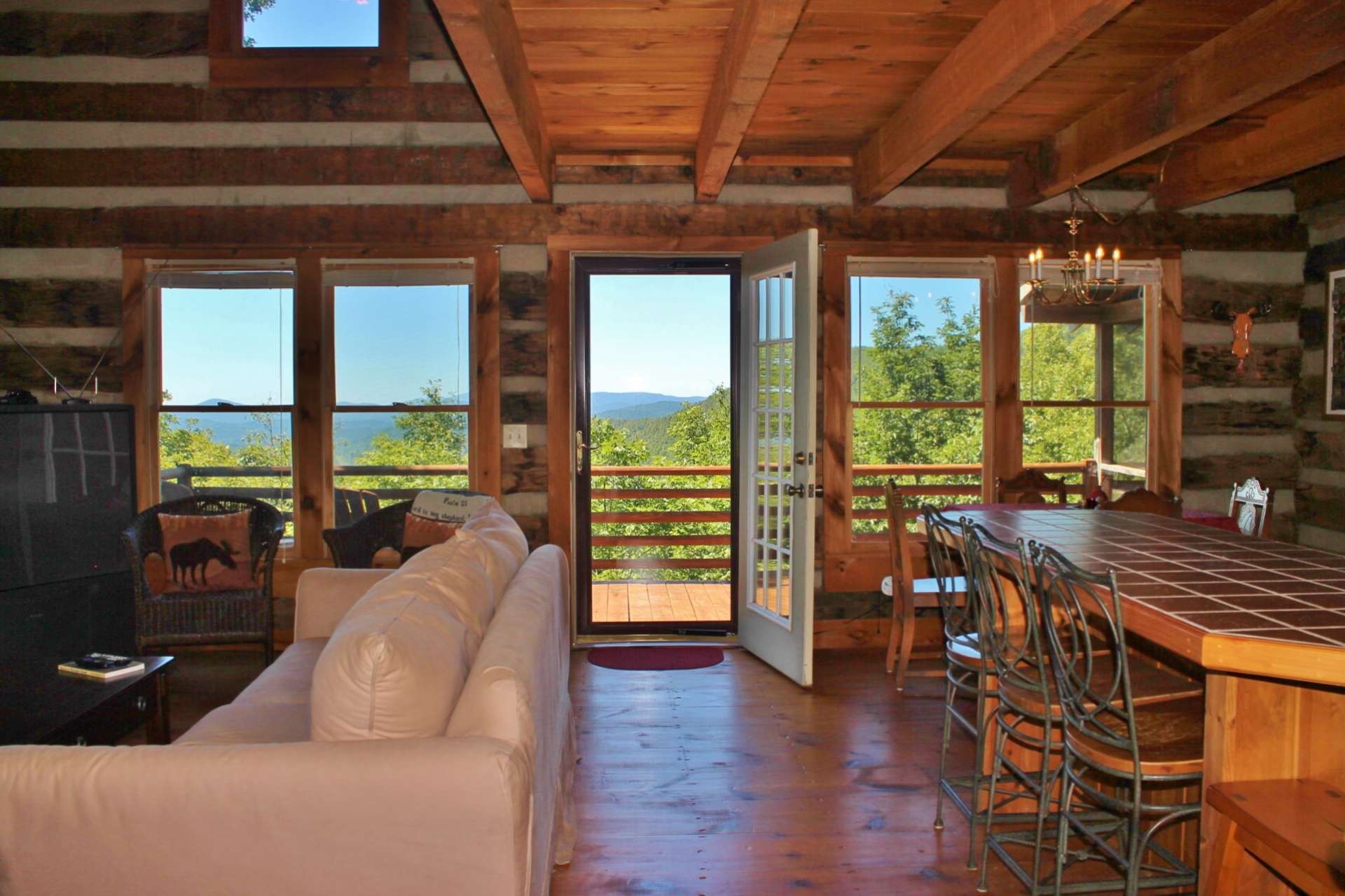 The open floor plan, with wide plank wood floors throughout, provides an easy transition from the living area to the kitchen and dining areas, as well as to the outdoors for outdoor grilling, dining, and entertaining.  Notice the use of lots of windows and French doors showcasing the views.