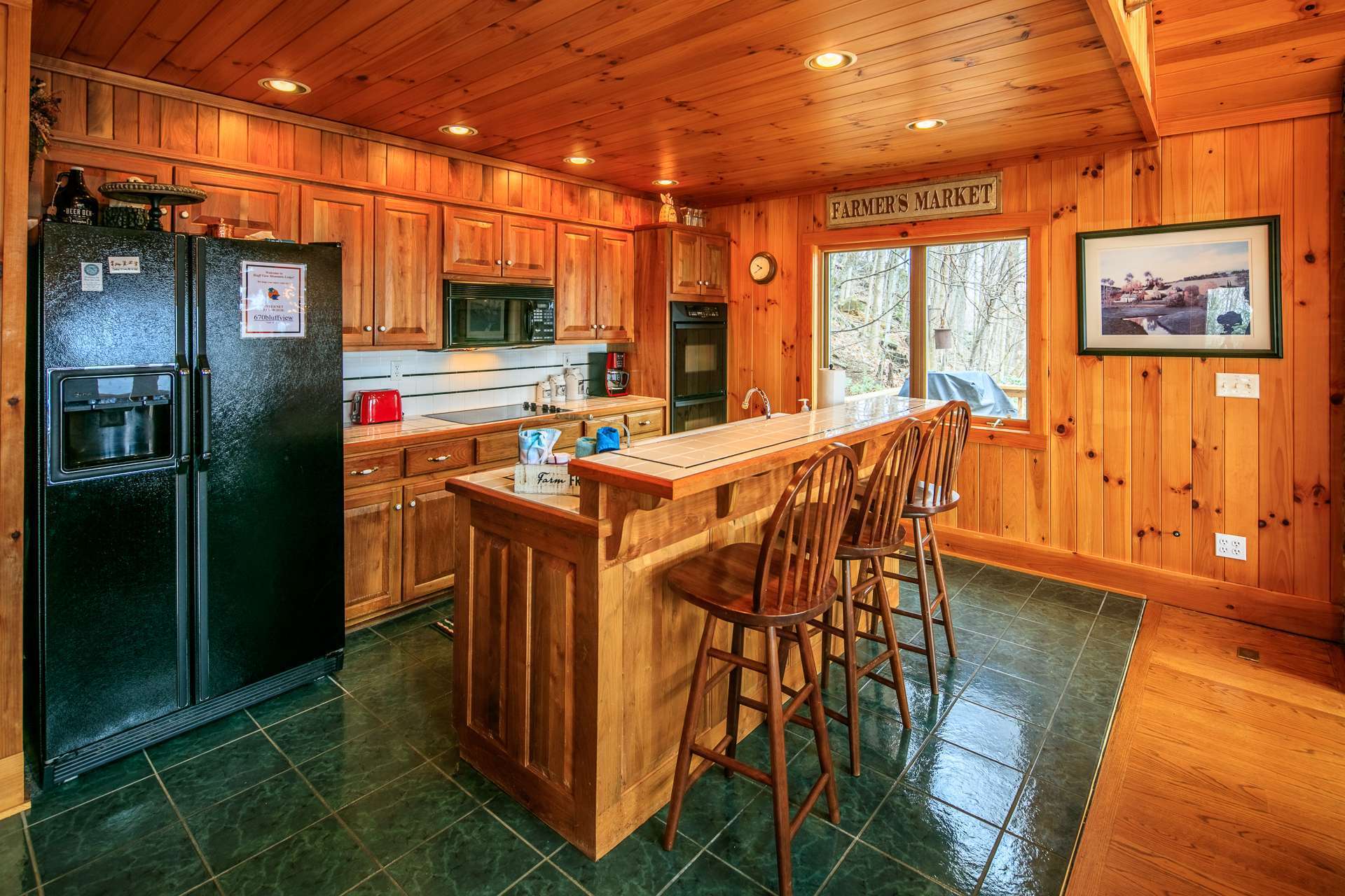 The kitchen features ceramic tiled floor and plenty of  work and storage space that includes a bar with seating.