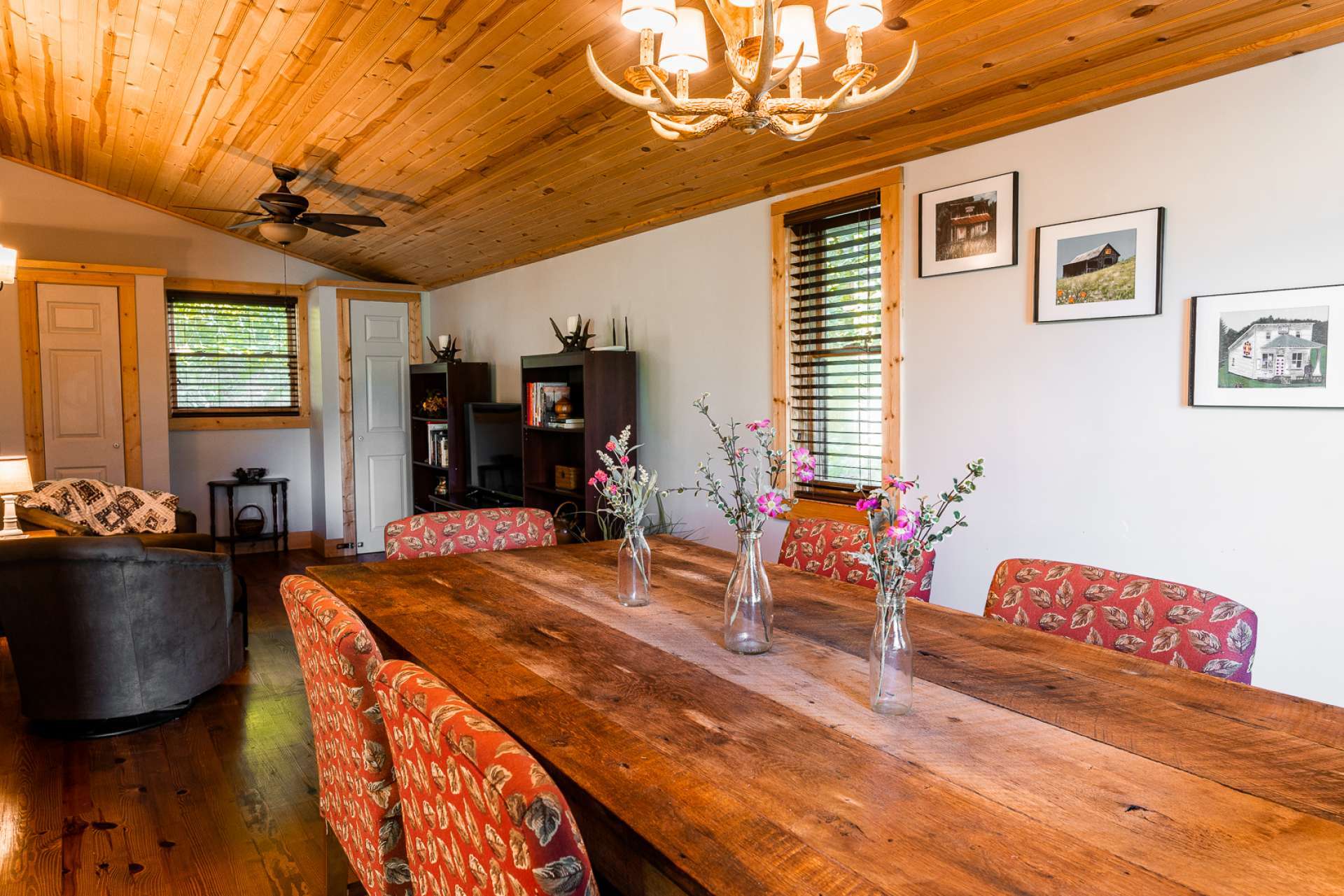 The dining area provides lots of space for entertaining.   This cottage is offered furnished. Notice the stunning dining table, handcrafted by a local artist.  At the end of the dining area is a space currently utilized as a den area with seating and TV.