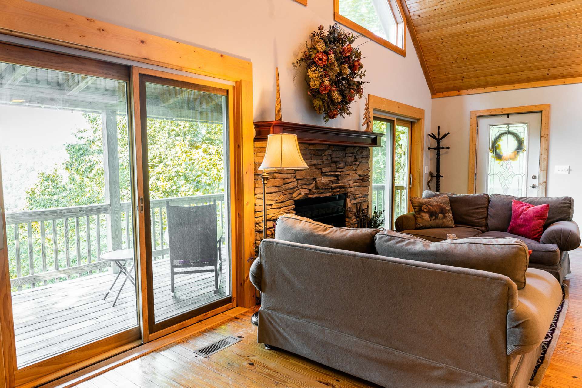 The living area features wood floors, a stone fireplace to warm up those cool winter evenings, and a wall of windows filling the space with natural light.