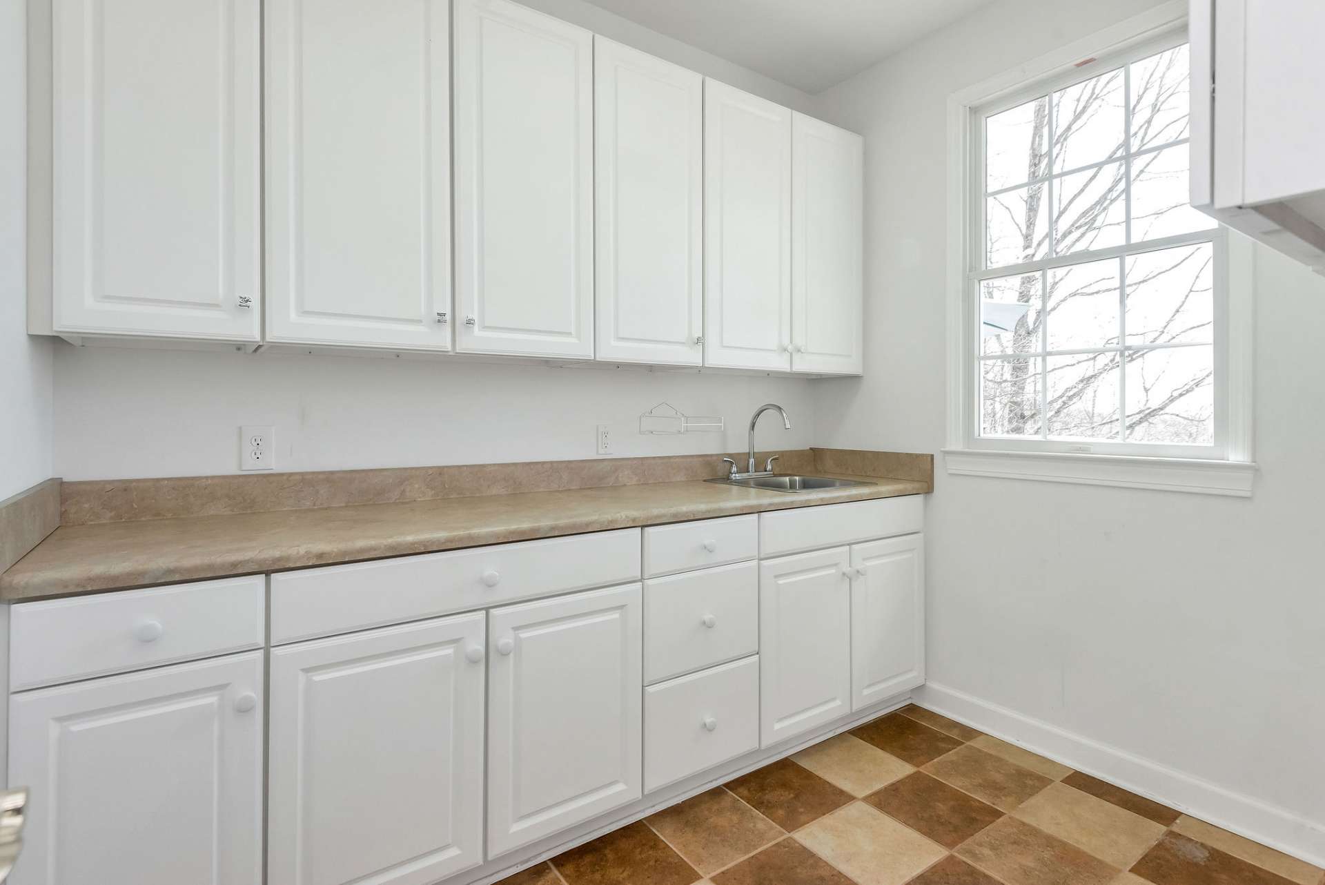 Main level laundry room provides a spacious countertop stretching along one wall, providing ample space for folding clothes. Abundant cabinetry offers plenty of storage for laundry supplies, cleaning products, and household essentials.