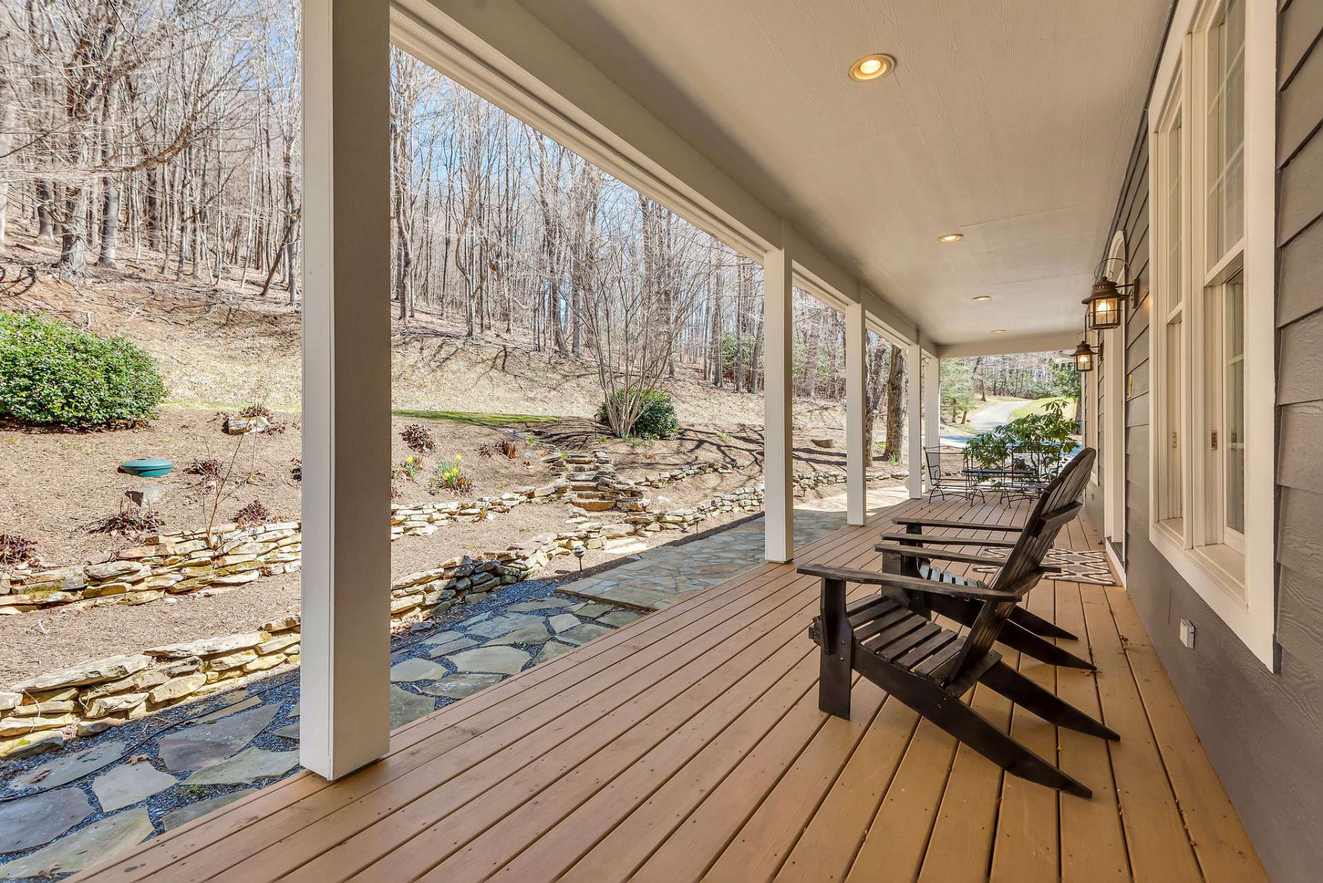 Inviting covered front porch offers a shaded retreat from the sun and also creates a welcoming ambiance for guests. The stone walkway leading up to the porch provides a charming transition from the driveway to the front door, guiding visitors with its natural beauty and elegance. Lined with lush landscaping, the walkway enhances the curb appeal of the home and sets the tone for the inviting atmosphere that awaits inside.