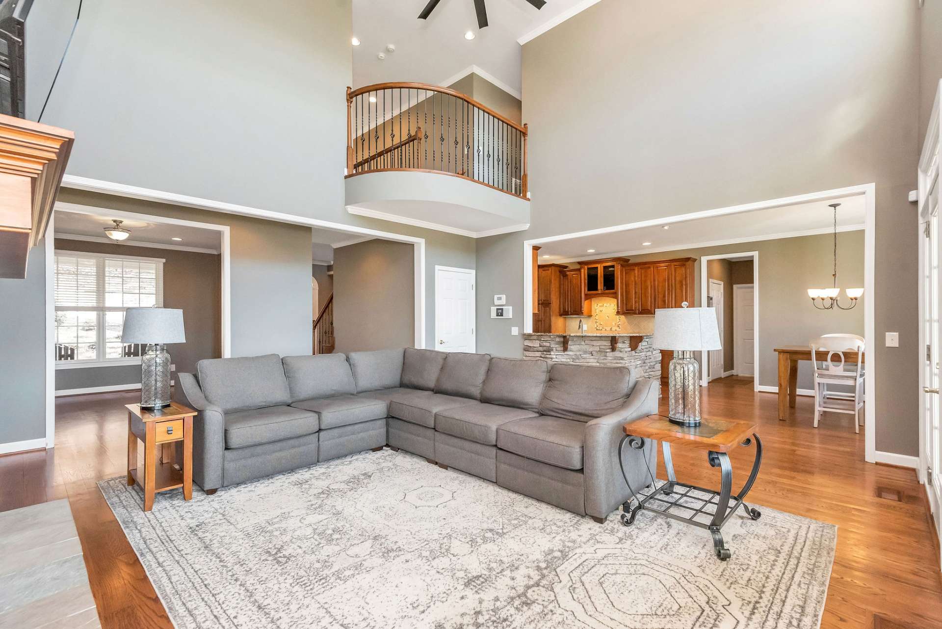 Above the living room, a rounded open balcony with wrought iron railing adds architectural interest and visual appeal, creating a sense of depth and dimension to the space.