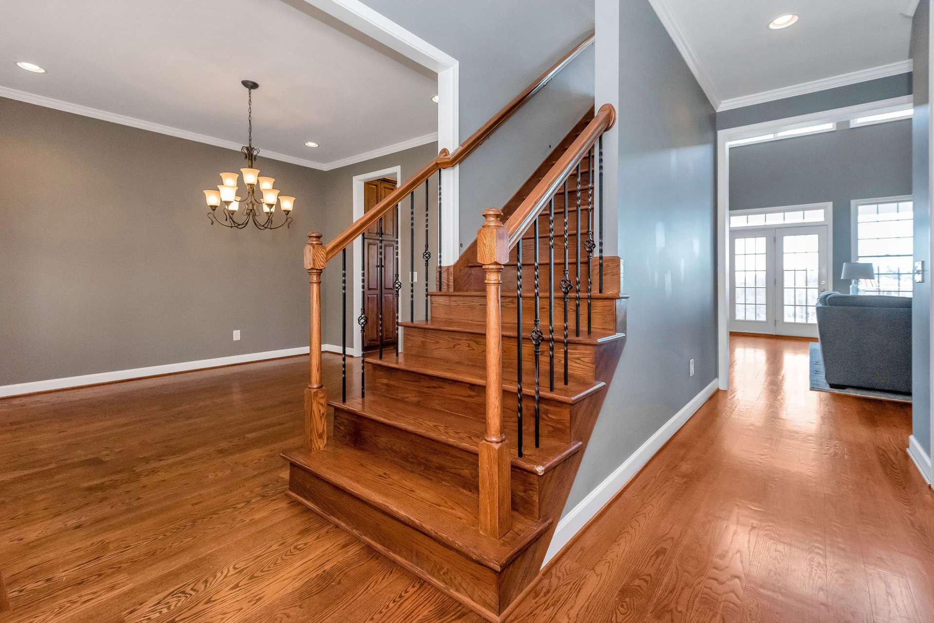 Bathed in natural light pouring in through the windows above, the vestibule provides access to the music room/front parlor on the right, the dining room on the left, the living room ahead, as well as the upper level.