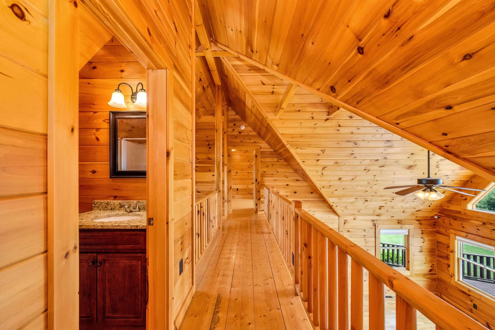 A stunning walkway connects the upper-level bedrooms, offering a bird’s-eye view of the living area below and highlighting the home’s dramatic ceiling architecture and exposed beams.