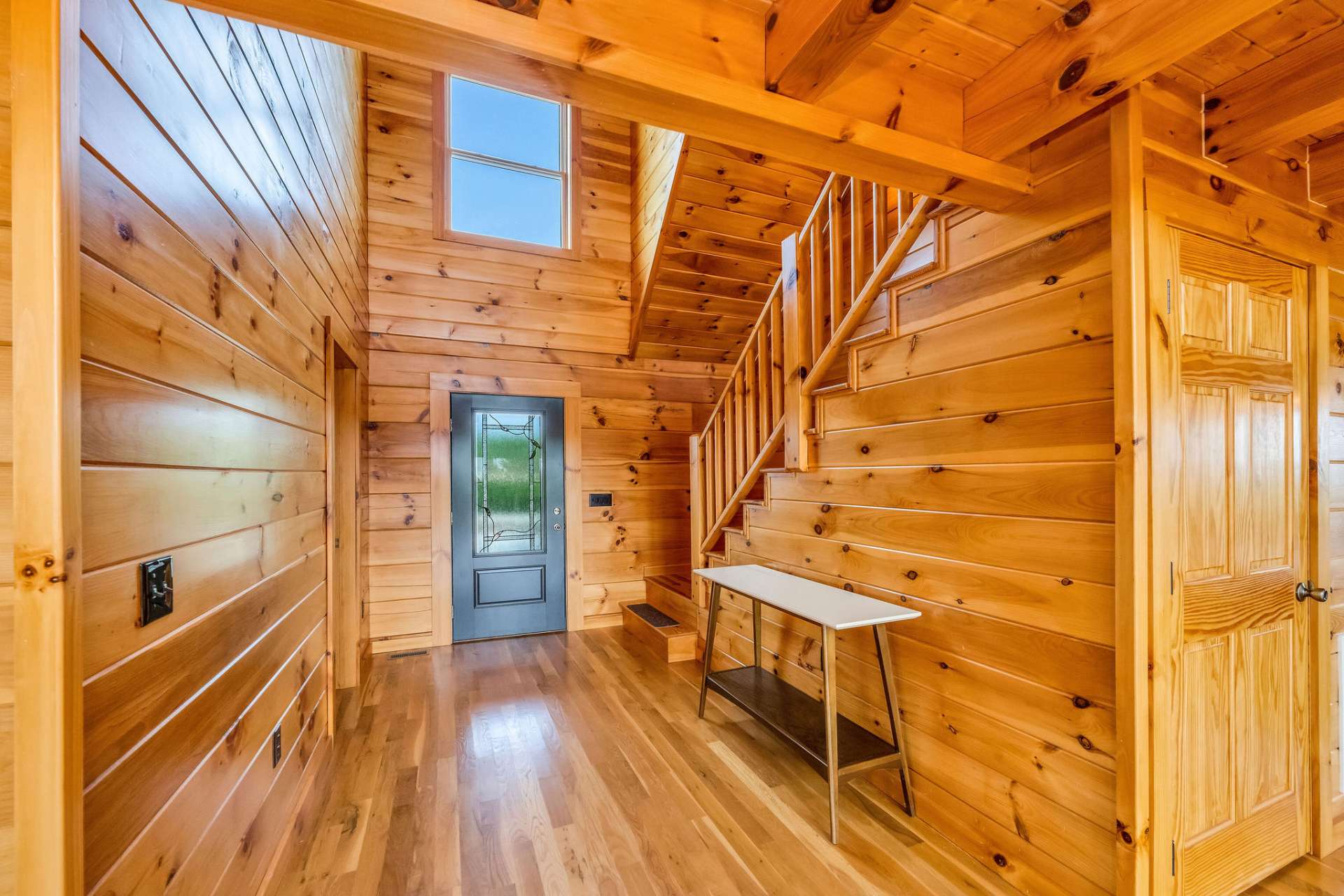 Welcome guests into a stunning two-story foyer showcasing tongue-and-groove pine walls and ceiling, creating a bright and inviting first impression.