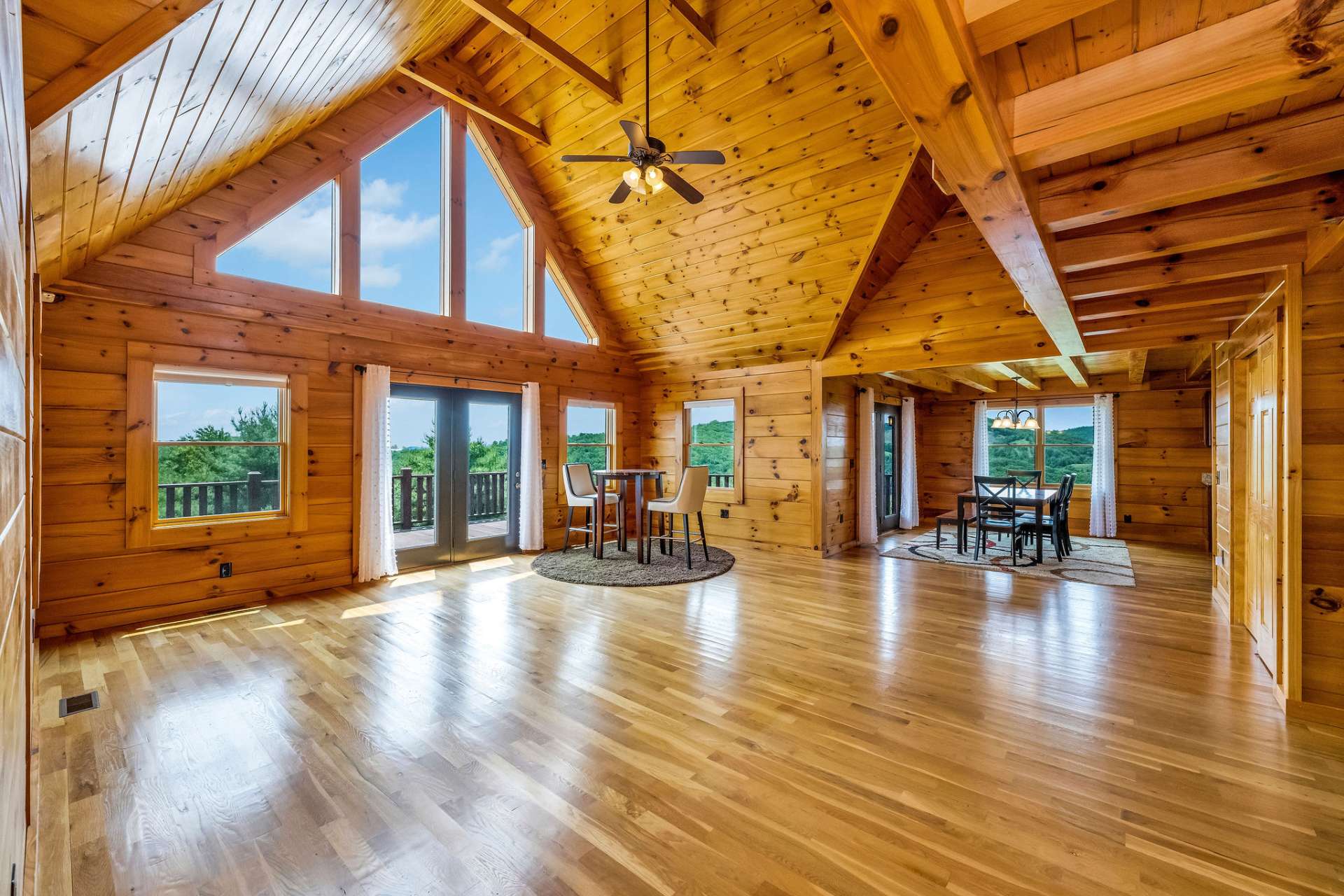 Expansive living area with soaring vaulted ceilings and gleaming hardwood flooring, creating a bright and welcoming space filled with natural light.
