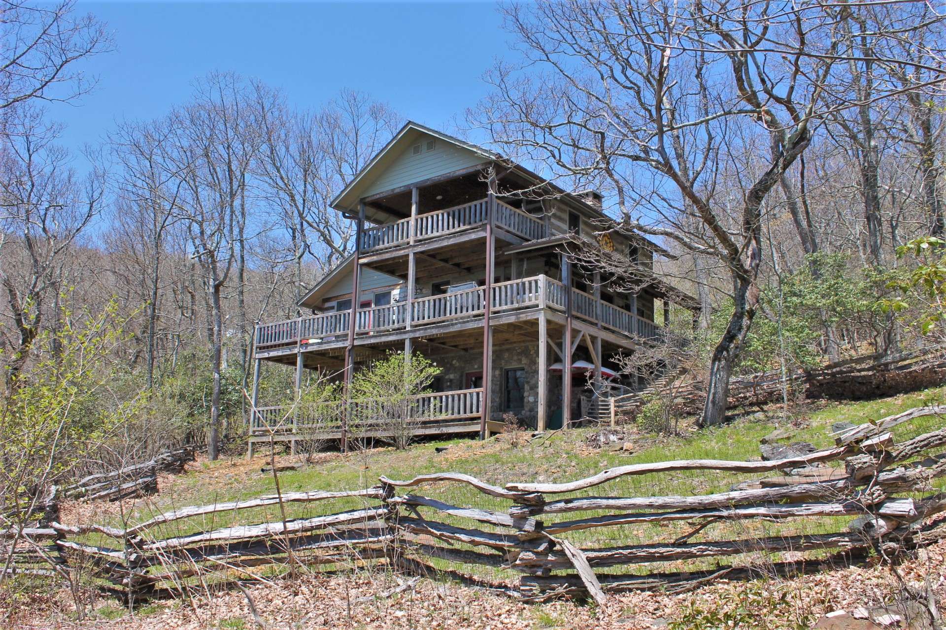 A covered front porch welcomes you while a large covered back deck lures you to relax and enjoy Nature's classroom with unobstructed layered long-range views here in Stonebridge, a private log cabin community located in the Todd area of Southern Ashe County.