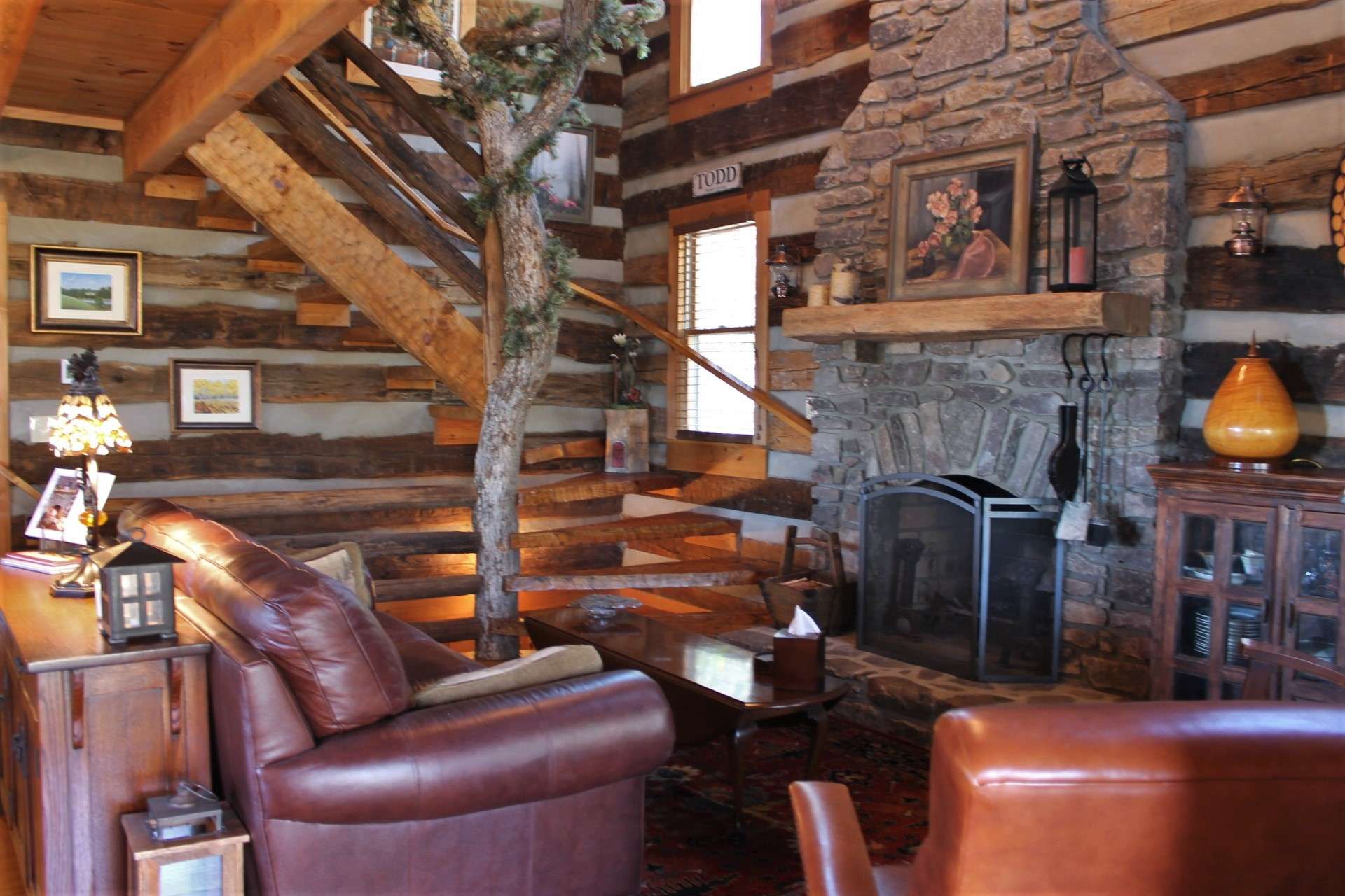 The vaulted great room is both charming  and charismatic with its wide plank wood floors, unique newel post, and a native stone  wood-burning fireplace.
