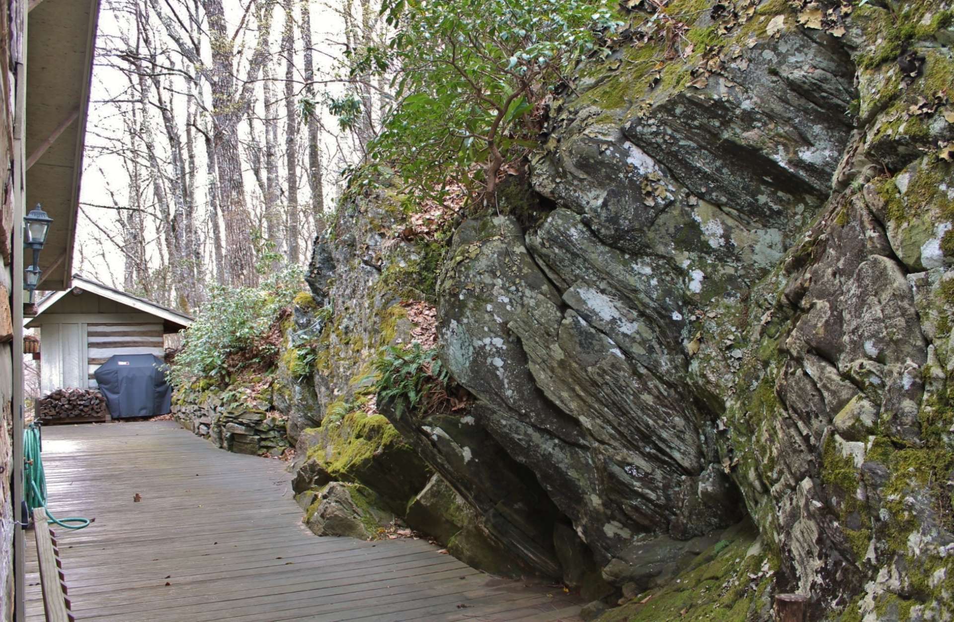 The covered front porch wraps around the side to the back deck where friends and family gather for a barbecue or just sit and enjoy the serenity of living in the mountains.  A massive boulder and rock formation runs the entire side of the cabin creating a conversation item for guests.