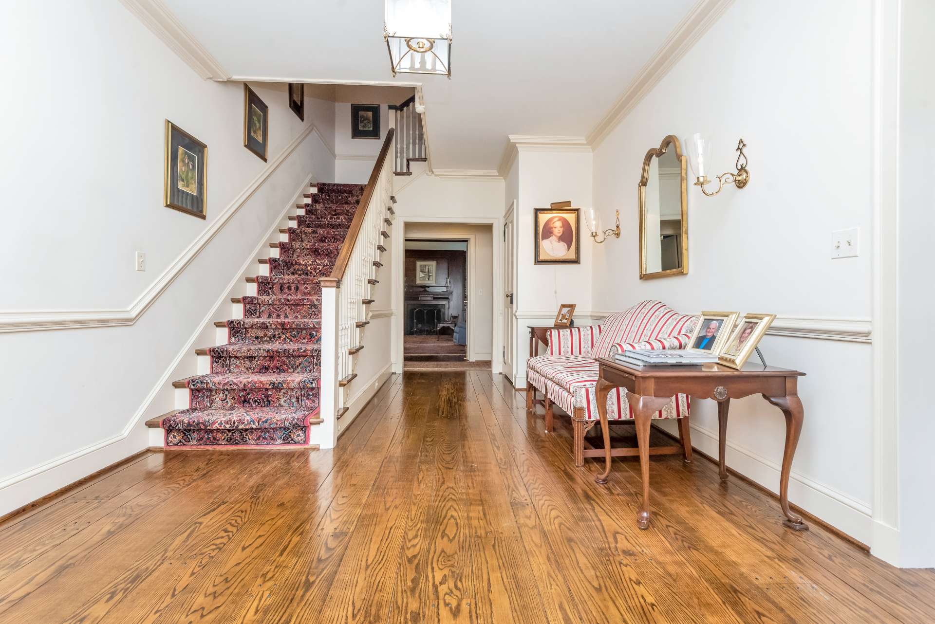 A grand foyer is flanked by the parlor on the left, and the formal dining room on the right. Notice the beautiful wood floors with the notched accents.