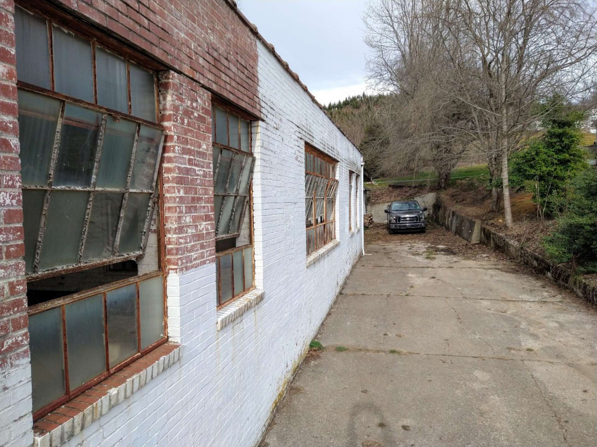 A 7,600 sq. ft. paved area wraps around the building on three sides, with a 6-inch well in a small well house at the back of the lot.