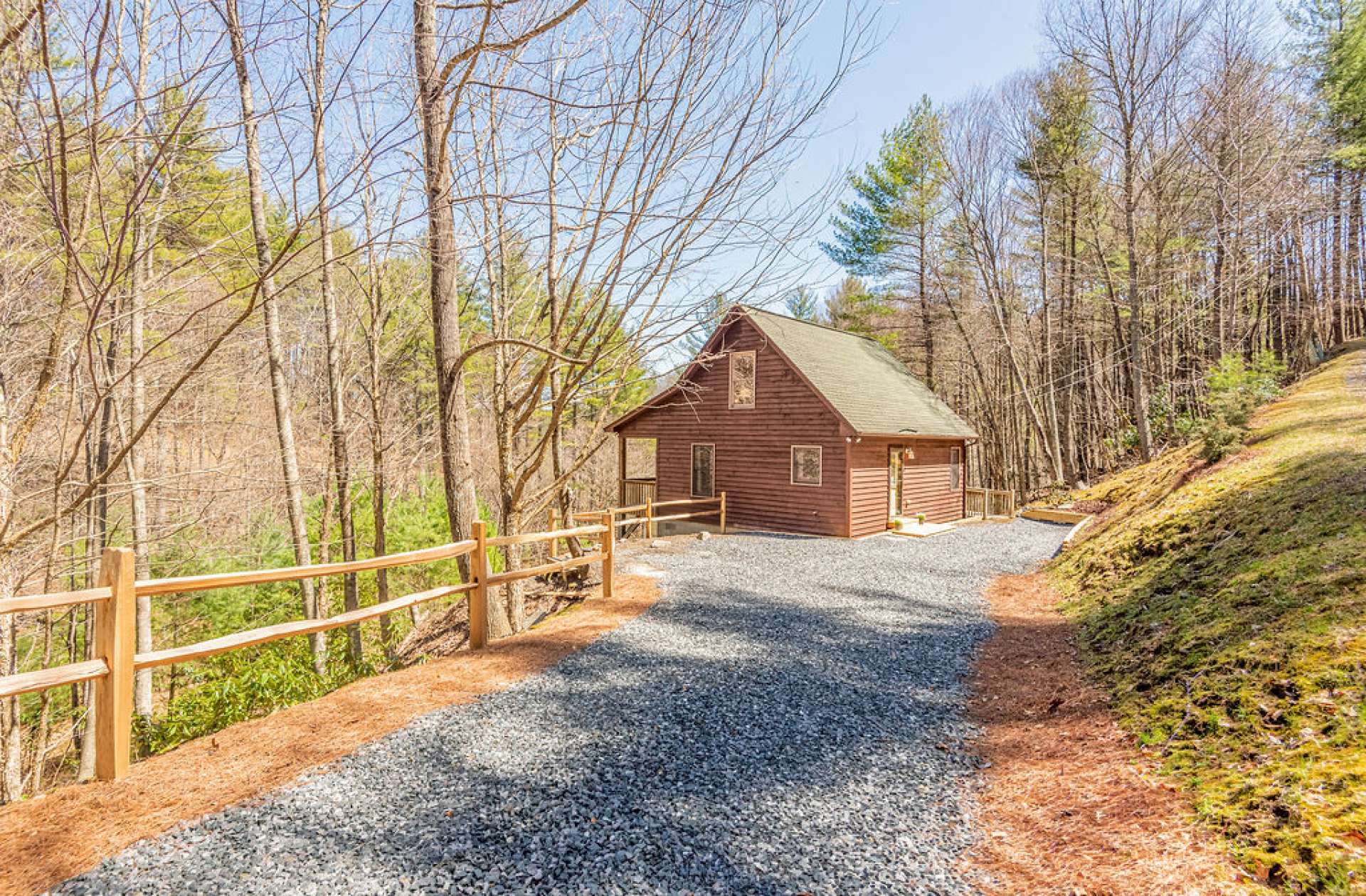 New split-rail fence borders the newly graveled driveway of this sweet home.