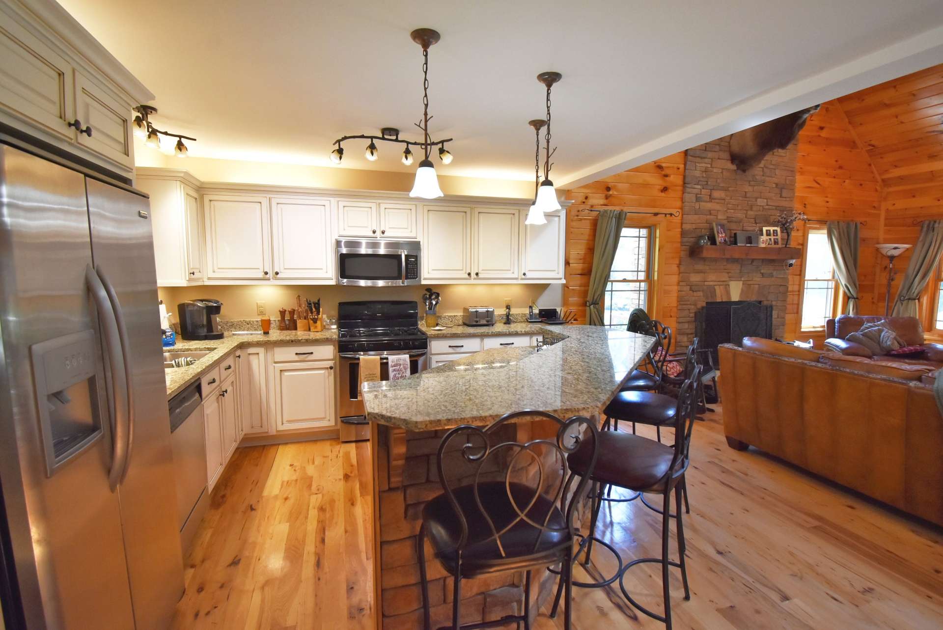A gracious kitchen with off-white cabinets brightens the cabin and wood floors gleam with reflected light. The island seats four, and the living room is large enough to add a table if desired.