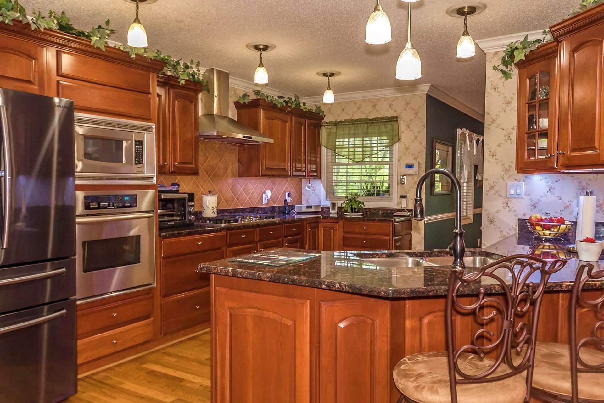 This beautiful gourmet kitchen features stainless appliances including gas cooktop, granite countertops, and plenty of work and storage space that includes a bar with seating.