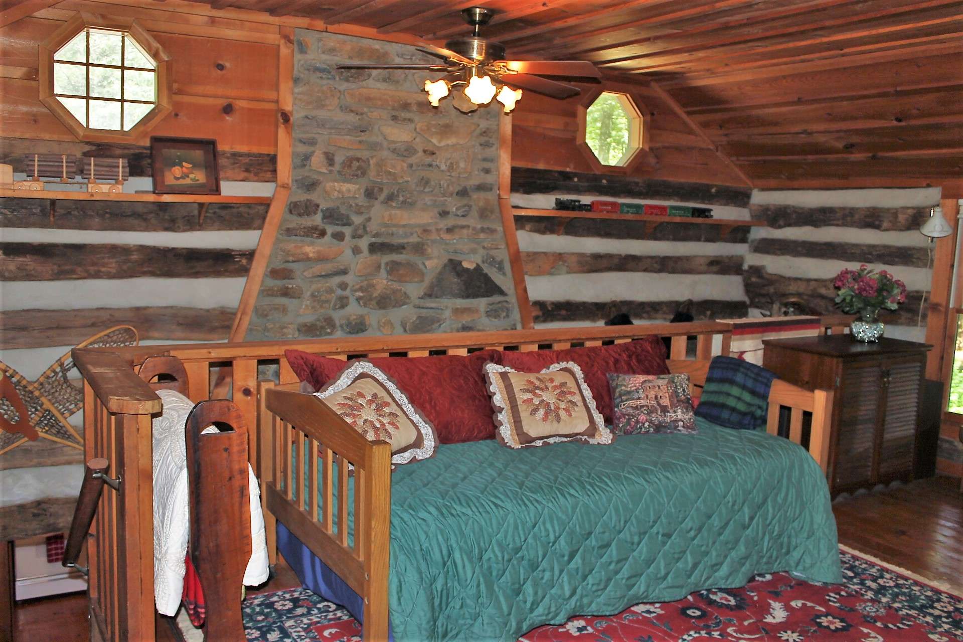 The stone fireplace is visible from the upstairs open loft which is set up as an additional sleeping area