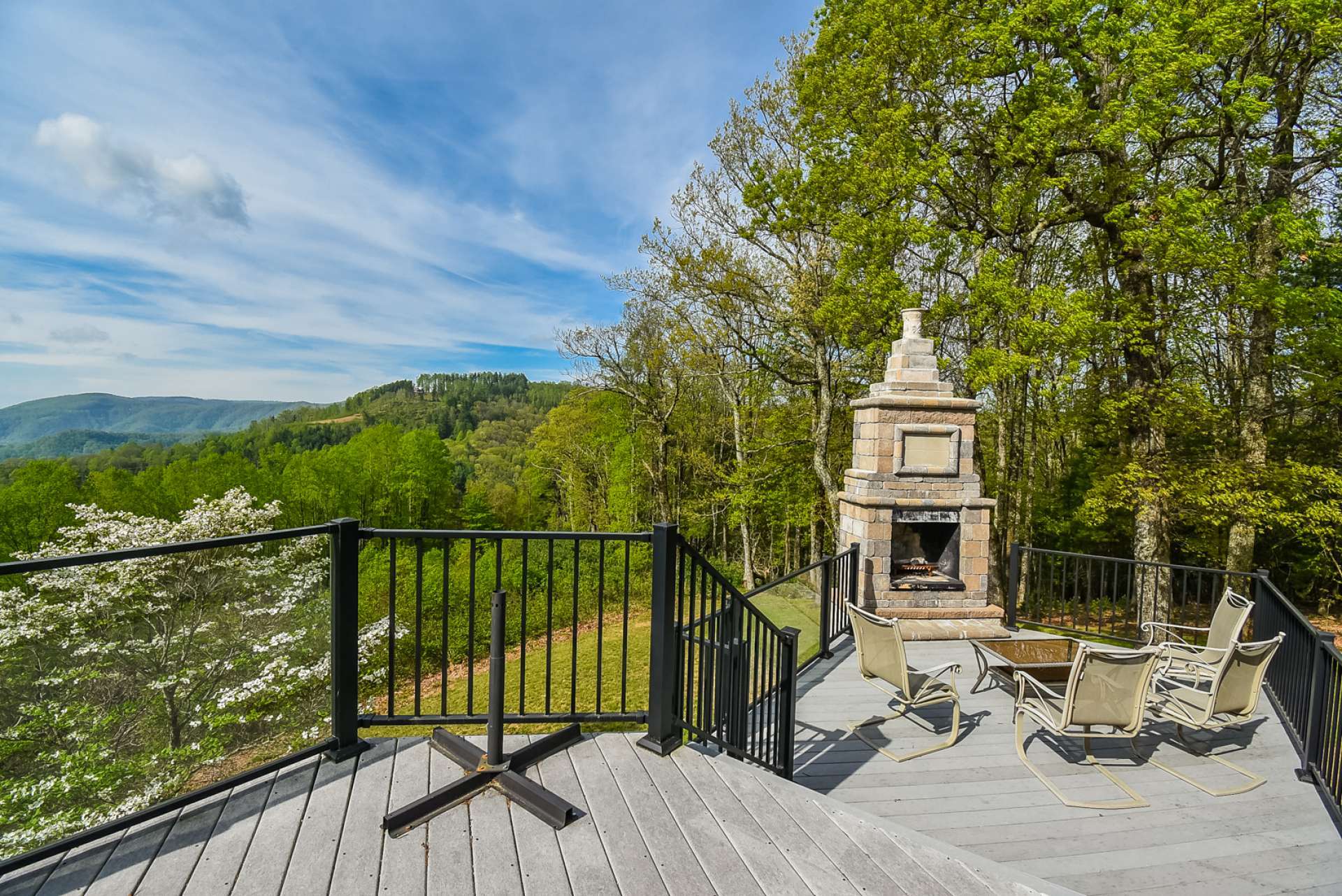 This home is designed for entertaining. This expansive open deck offers wrought iron accents, composite decking, a stone wood-burning fireplace for anytime ambiance and cool evening warmth, and sweeping long range layered views.