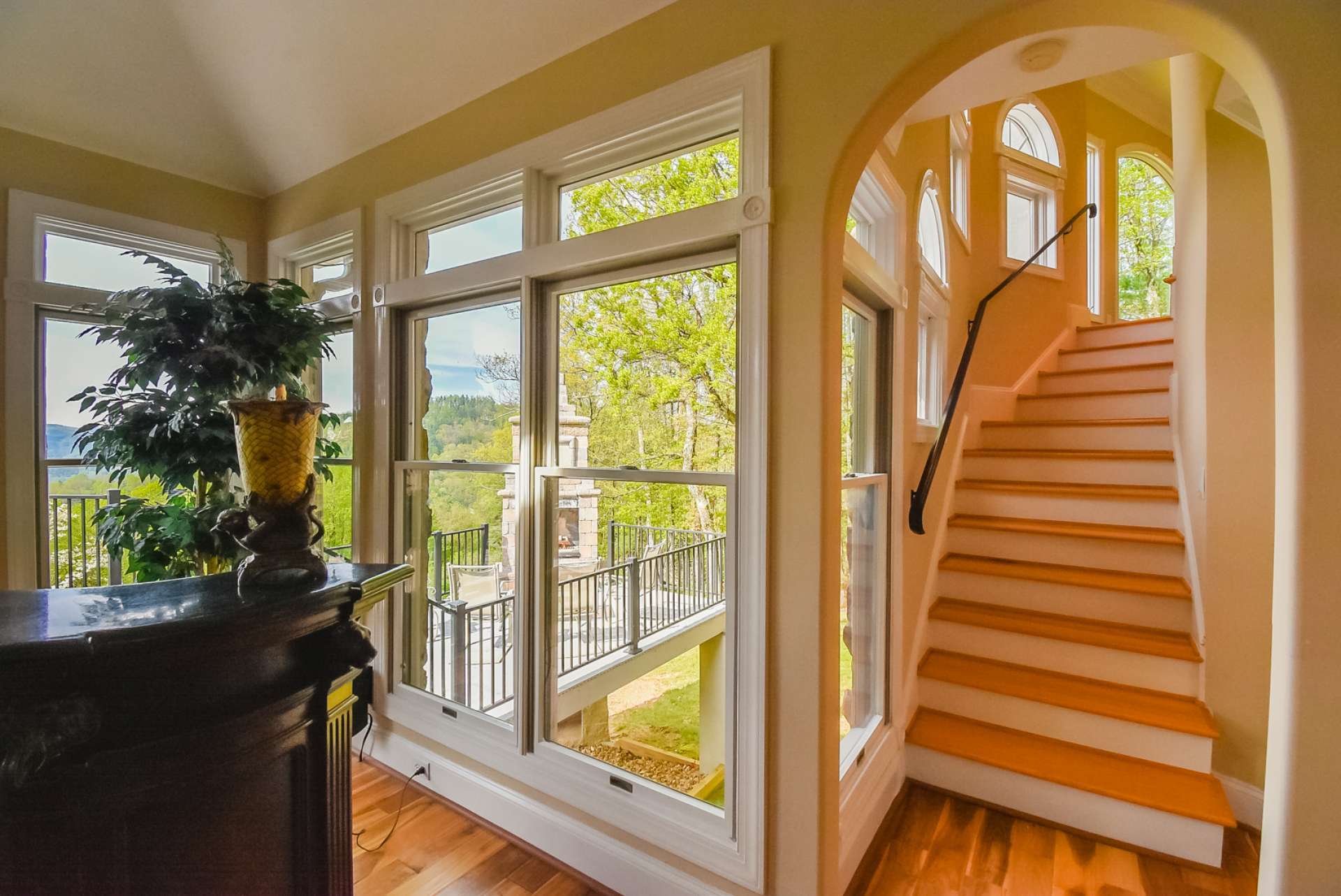 An arched doorway leads to the second level. Notice the use of abundant windows filling the home with natural light and allowing you to enjoy the outdoors from inside.