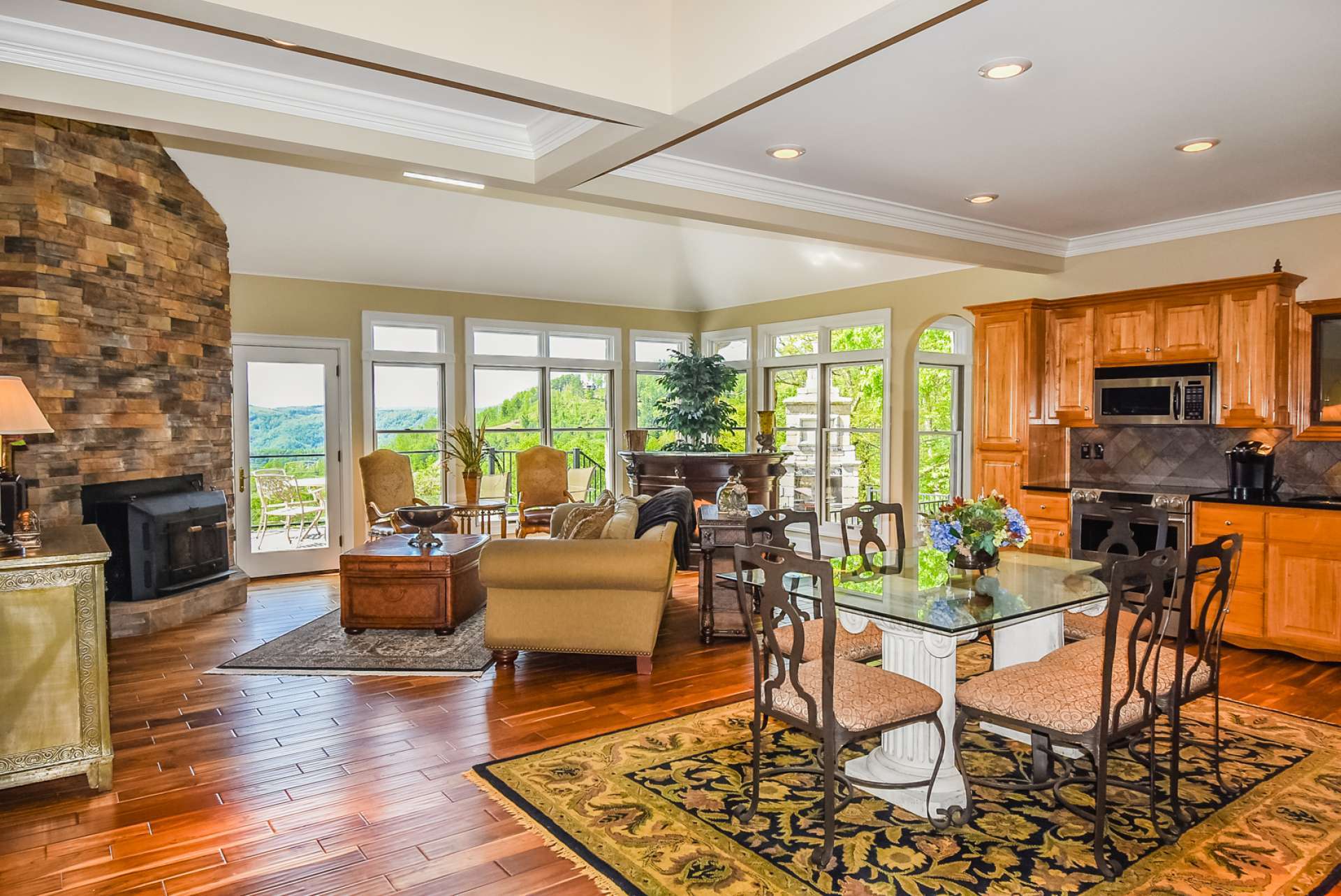 The light filled great room features Teak flooring, stone fireplace with wood stove insert, and a wall of windows to enjoy the views.