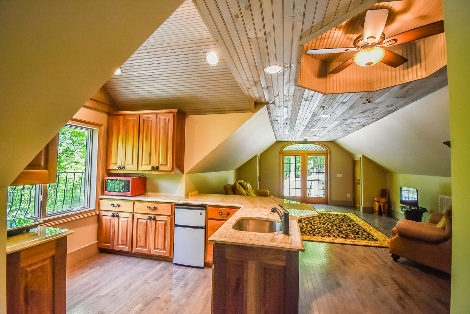 The apartment features a living area, kitchen and dining area, bedroom, and full bath. Notice the granite counter tops and walnut cabinets in the kitchen area and the details in the wood ceiling