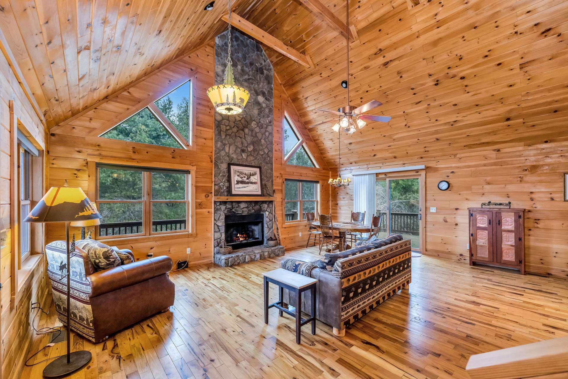 Spacious open great room with a stone fireplace, flanked by windows, as the focal point.