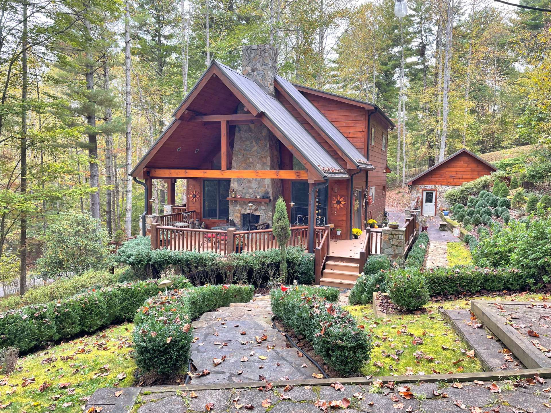 View of the side of the house with a vaulted deck with an outdoor fireplace. Well landscaped front yard.