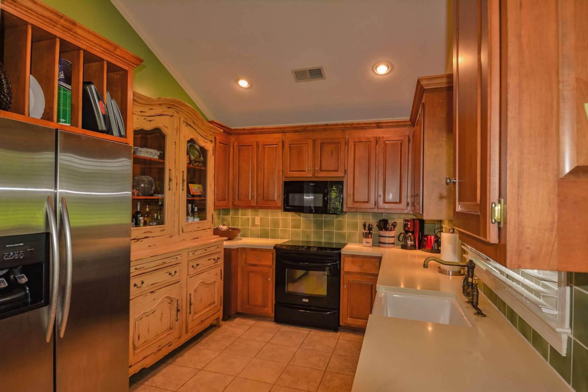 The galley style kitchen features Corian counters, tile flooring and ample cabinetry for work and storage space.