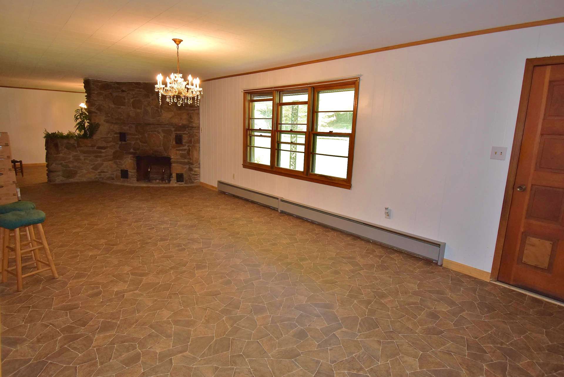 A large living room features new flooring and a unique stone wood burning fireplace as the focal point of the room.