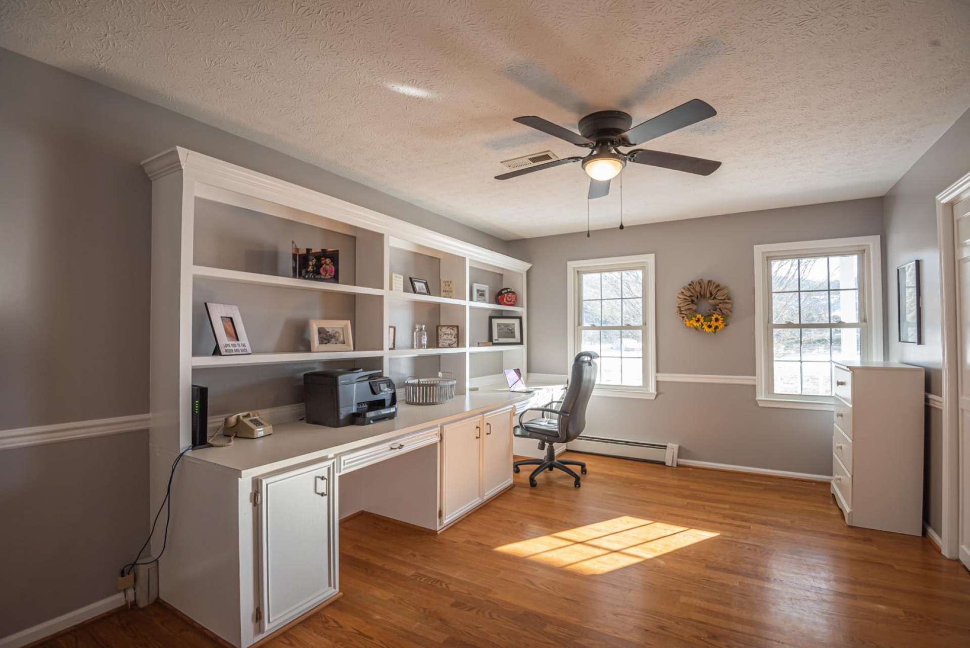 The original master bedroom has been converted into a large office with lots of windows, wood floor, and expansive storage space.