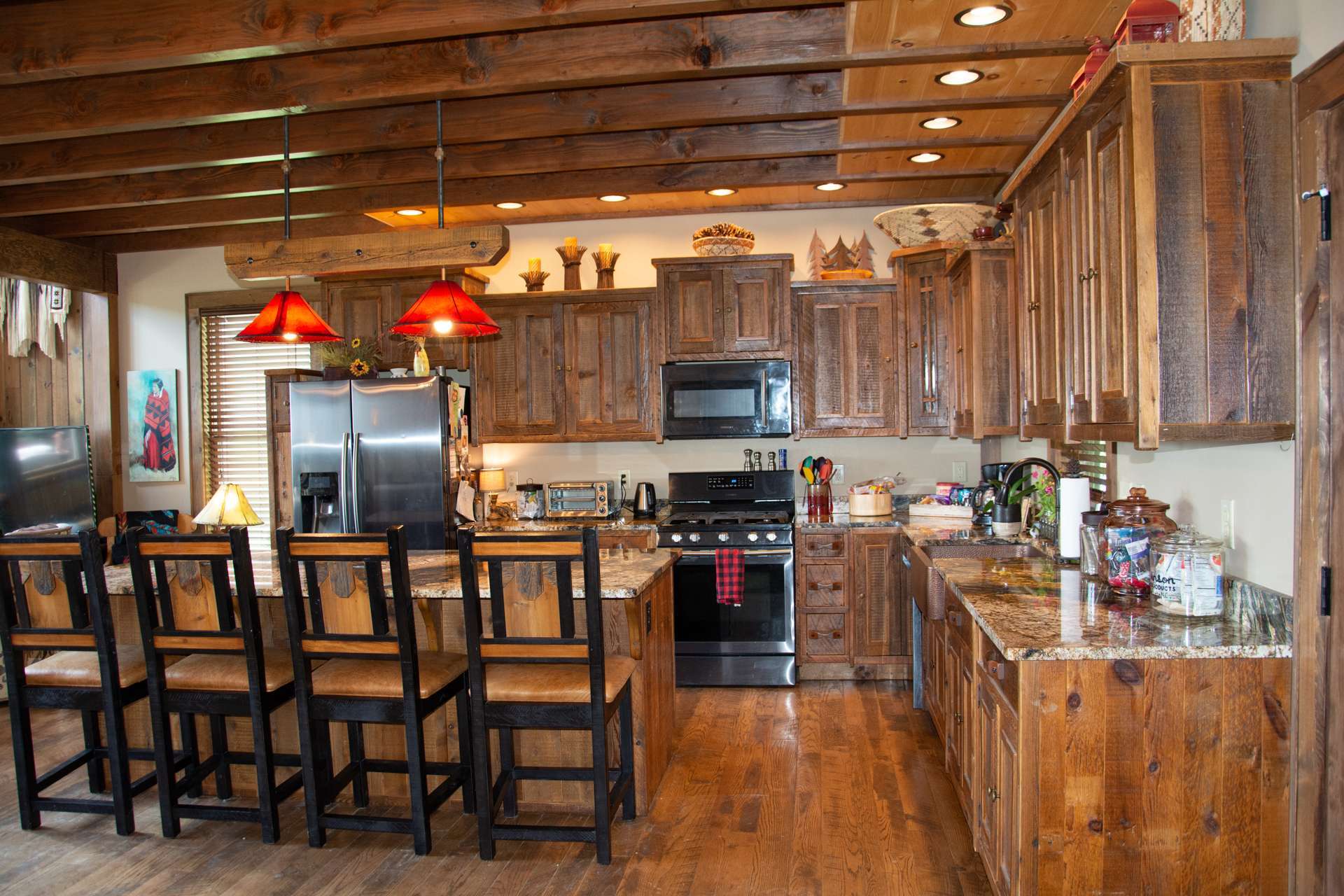 You are enveloped in modern luxury amid natural beauty and rustic details such as the exposed beams, reclaimed barn wood cabinetry, granite counter tops, hammered copper apron sink, gas range, and large island with bar seating in the kitchen.
