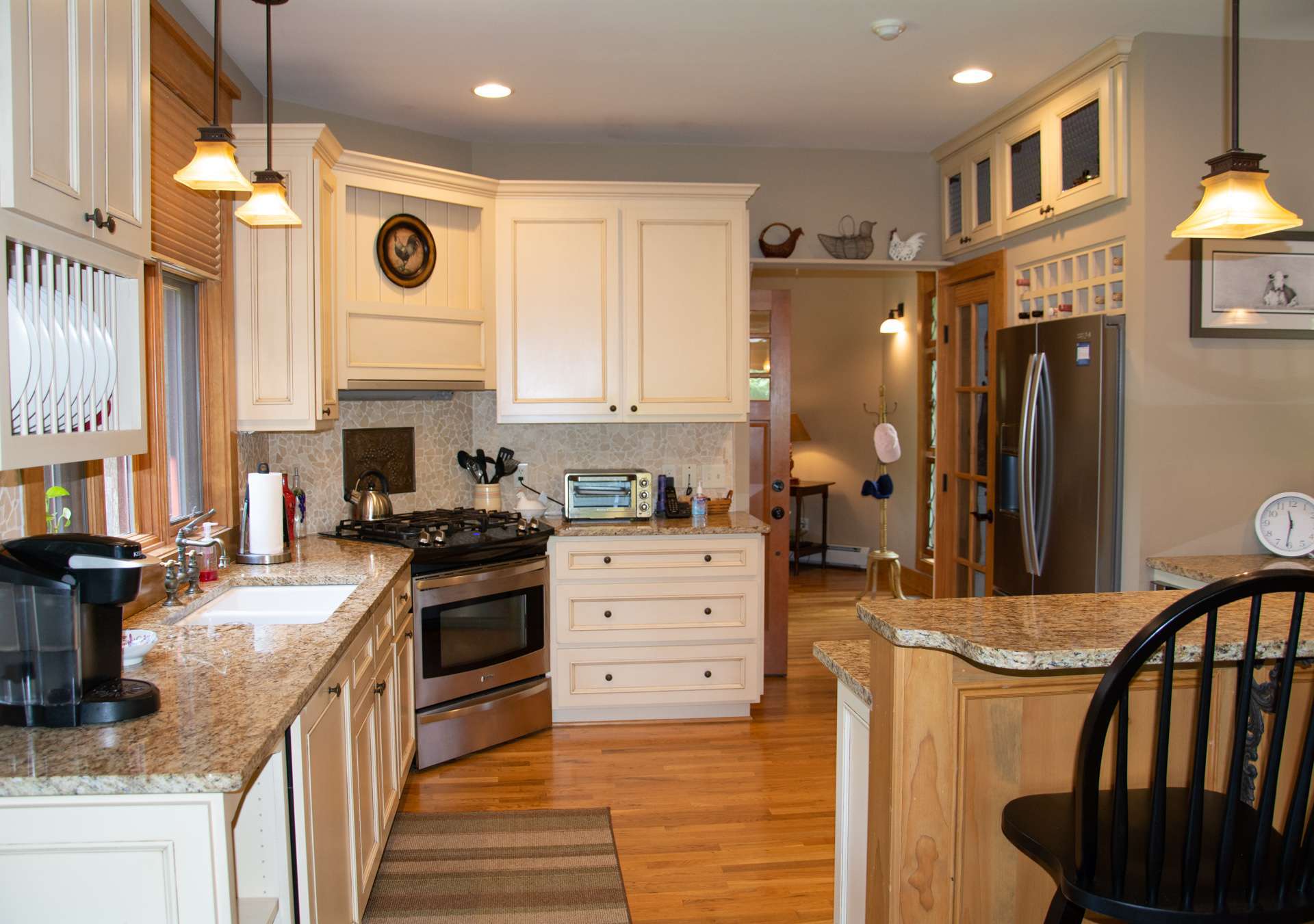 An entry hallway leads to a top of the line gourmet kitchen clad with premium finishes and fixtures, including custom cabinets with granite counter tops, stainless appliances, including a gas range, pantry and bar seating.