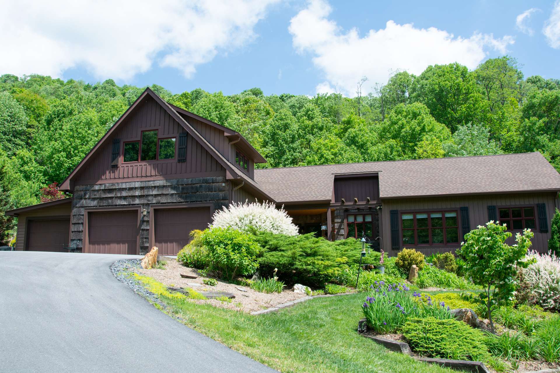 A beautiful entrance with newly paved driveway leads past a bold cascading creek.