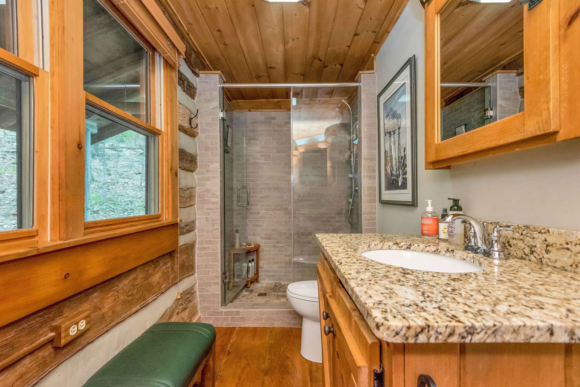Main level bath offers walk-in tile shower with glass door & rustic style vanity with granite counter tops.