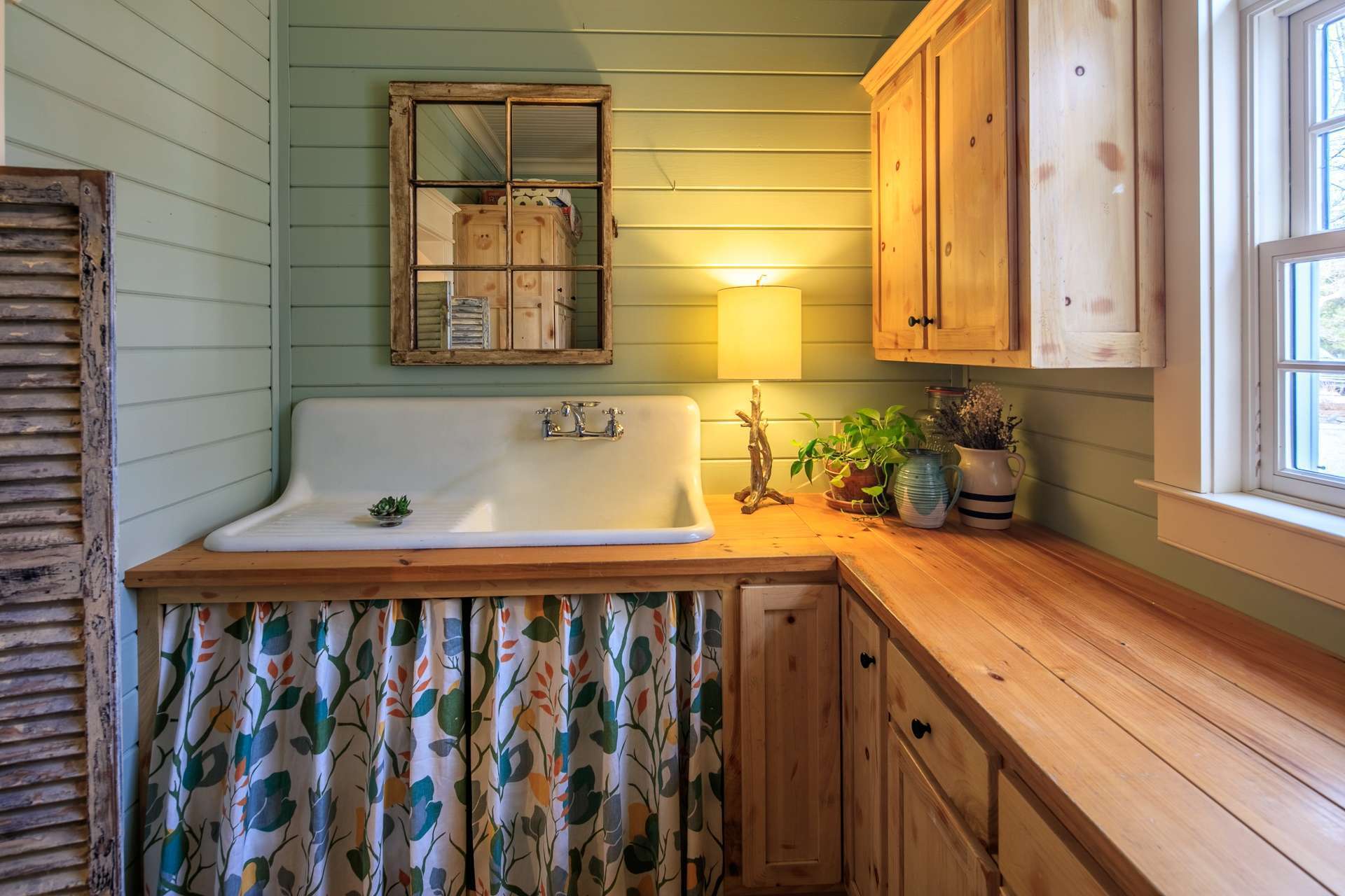 In keeping with the farmhouse styling, the laundry room features a farmhouse sink and custom cabinetry.