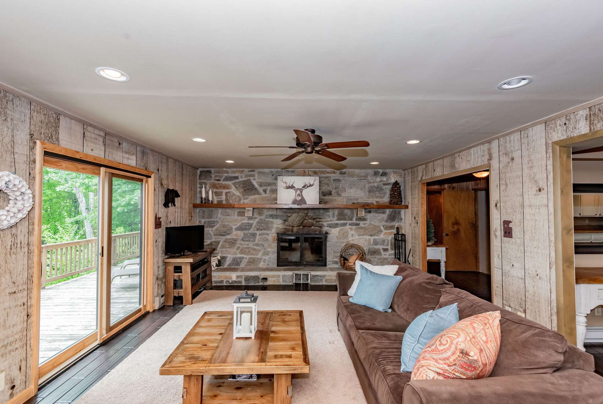 Rustic details enhance the atmosphere in the living area that includes a stone wood-burning fireplace and lots of glass to fill the area with natural light.