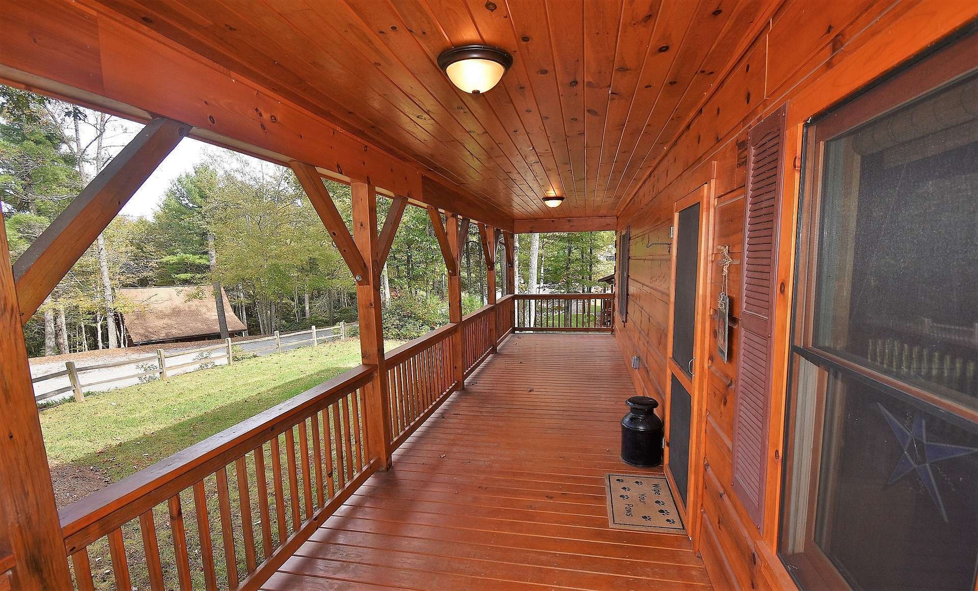 A long full length covered rocking chair front porch greets family and friends, bidding them to sit a spell and enjoy the peaceful sounds of Nature.