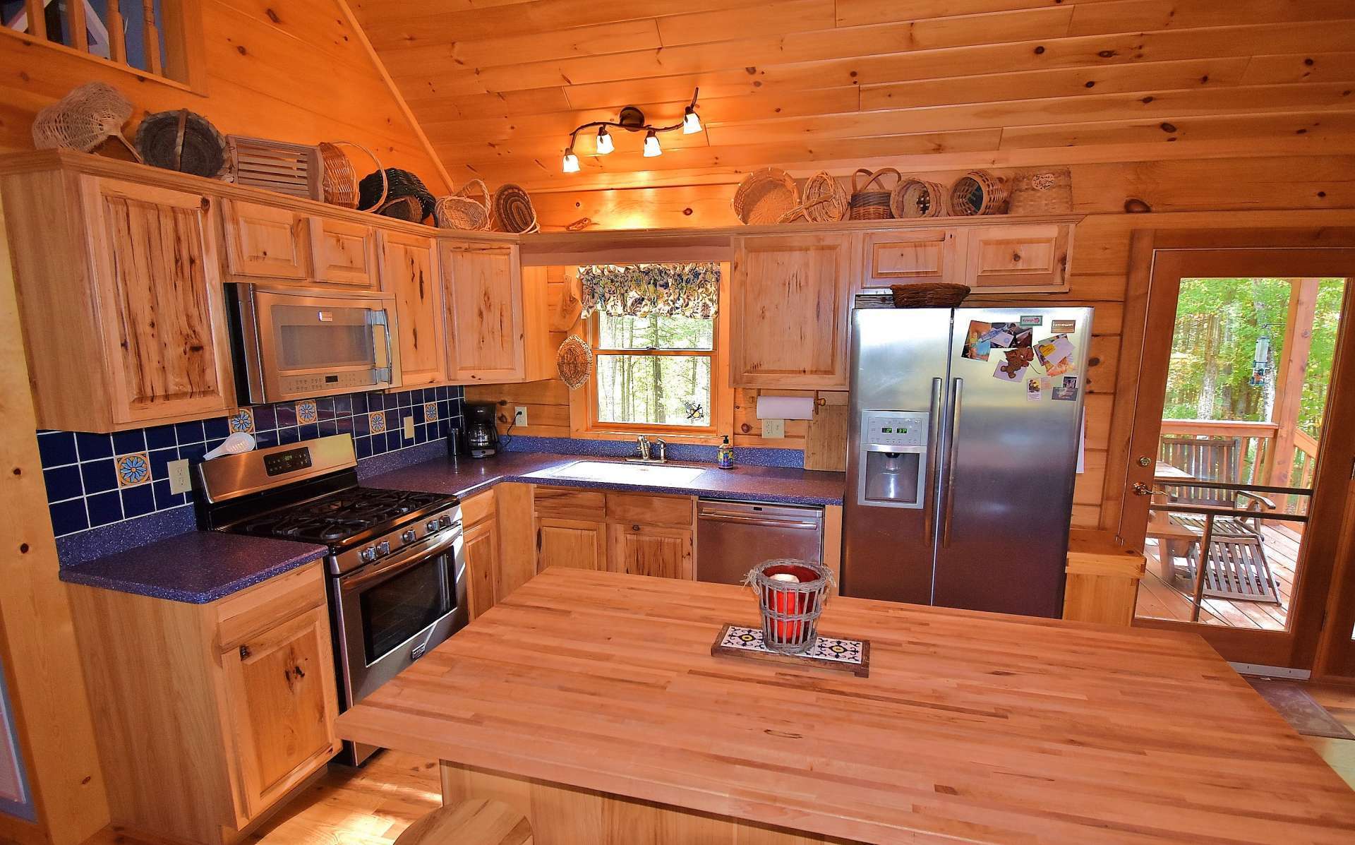 A fully equipped kitchen features stainless appliances, Hickory cabinetry, plenty of work and storage space, and easy access to the back deck for outdoor grilling and dining.