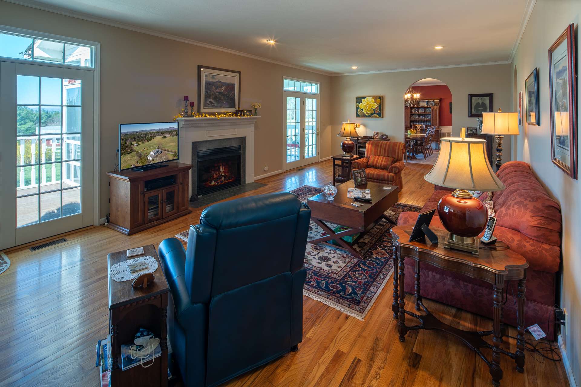 The spacious living area features a gas log fireplace and two sets of French doors to access the screened porch and outdoors.