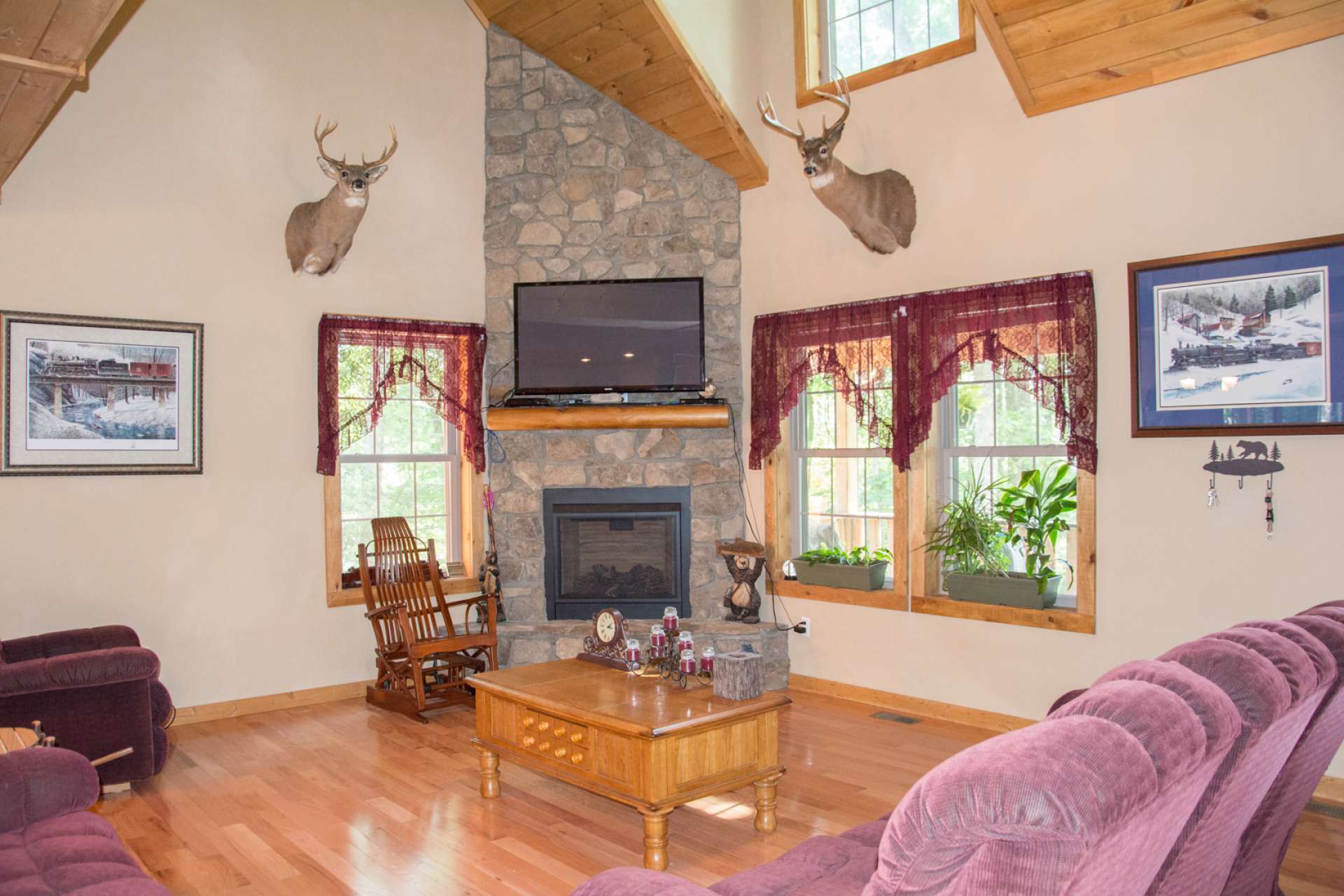 The cabin features an open great room boasting a stone fireplace with gas logs, vaulted ceiling, lots of windows filling the cabin with natural light, and wood floors radiating an inviting and warm ambiance as you enter the cabin.