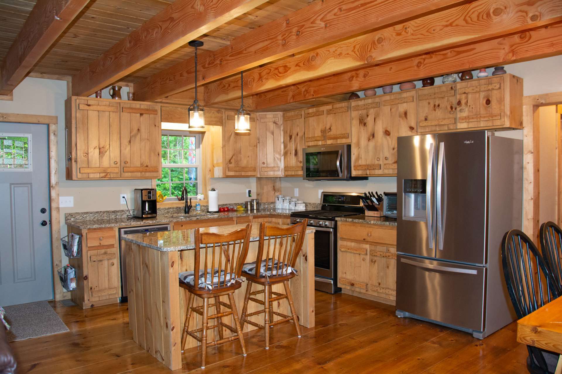 The kitchen features custom-built cabinetry, including an island offering additional work and storage space and bar seating. The kitchen also features granite counter tops and stainless steel appliances.