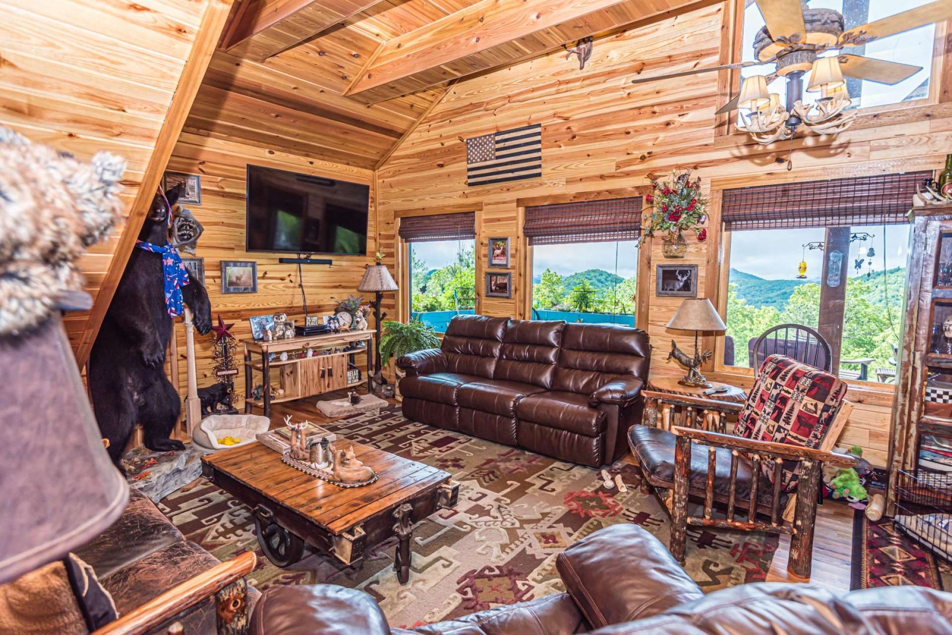 The vaulted great room features cedar covered exposed beams, cedar ceiling, wood floor, and abundant windows filling the cabin with natural light.