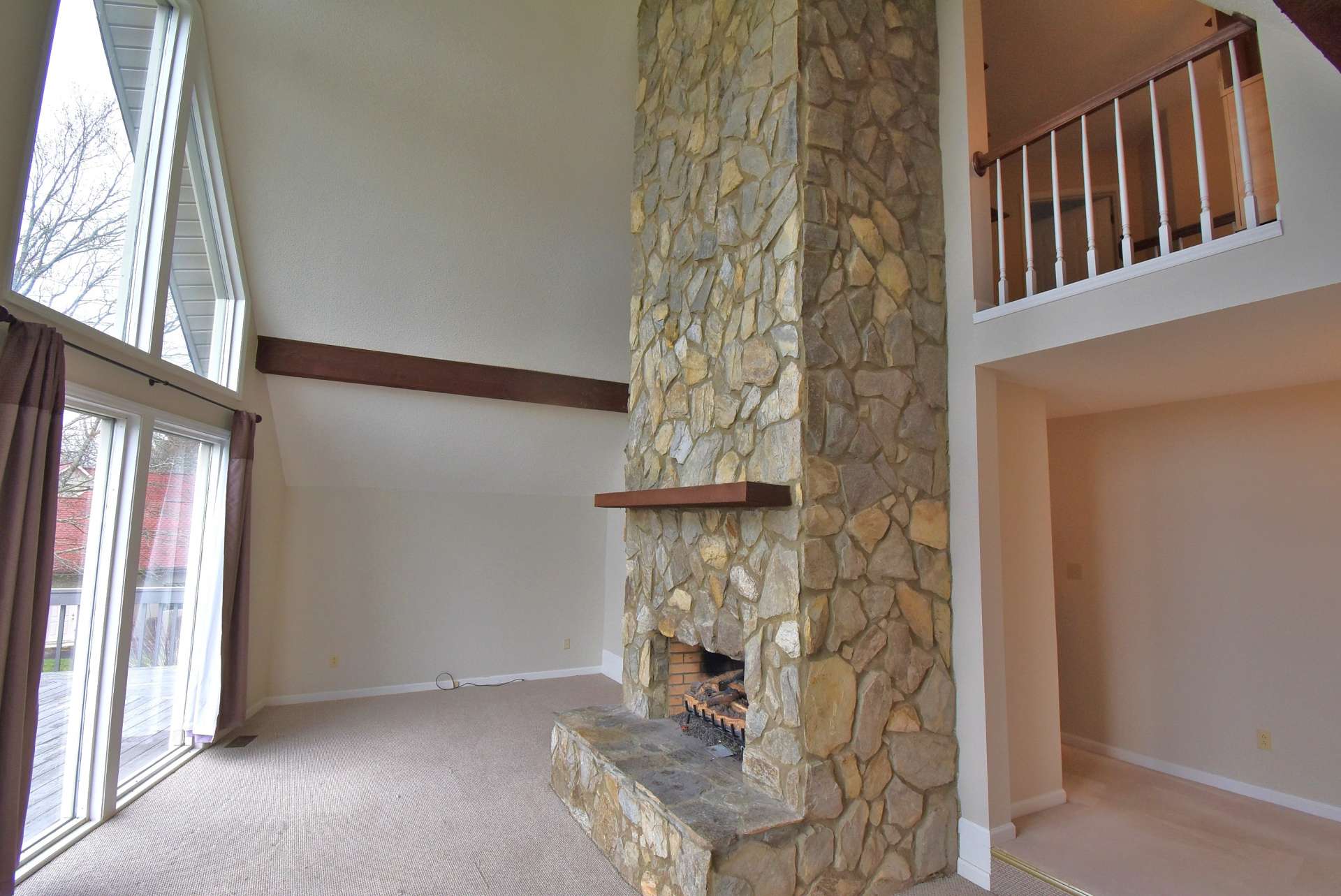 The living area features vaulted ceiling, a two-story stone fireplace with gas logs, and a wall of windows to fill the room with lots of natural light.