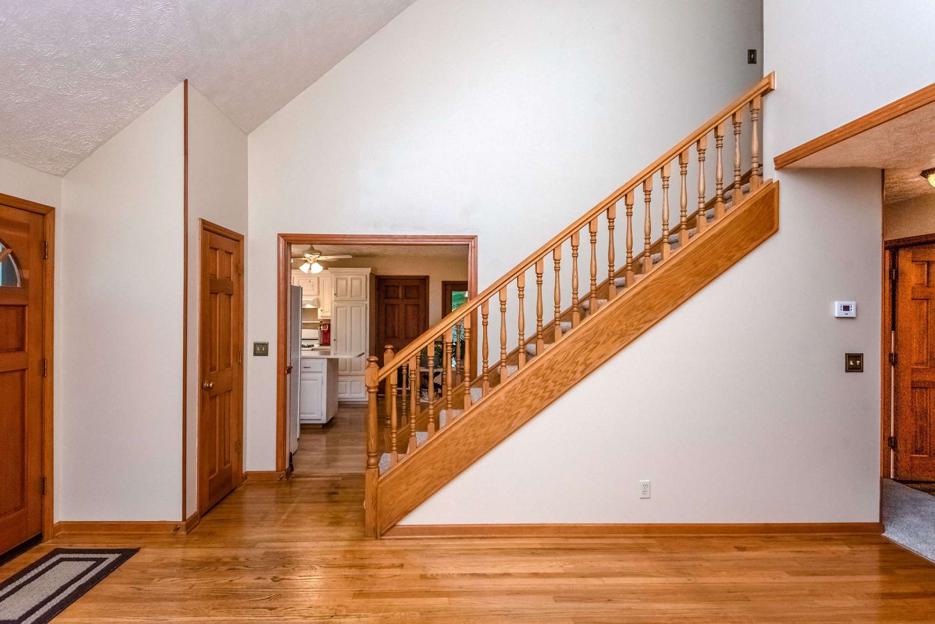 Front door leads to the living room featuring hardwood flooring and vaulted ceilings. The warm wood and freshly painted walls contrast beautifully.