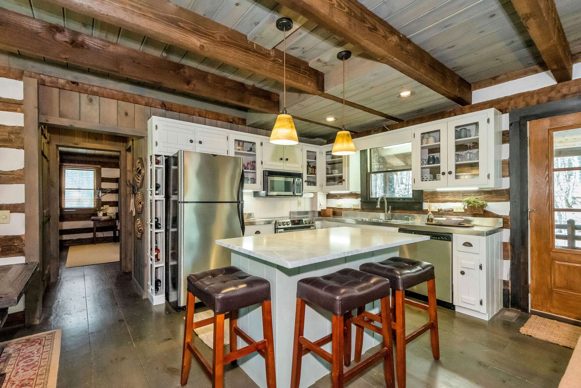 The kitchen maintains the rustic charm and functionality characteristic of cabin living. The light colored cabinets help to visually expand the space and make it feel more open and welcoming.
